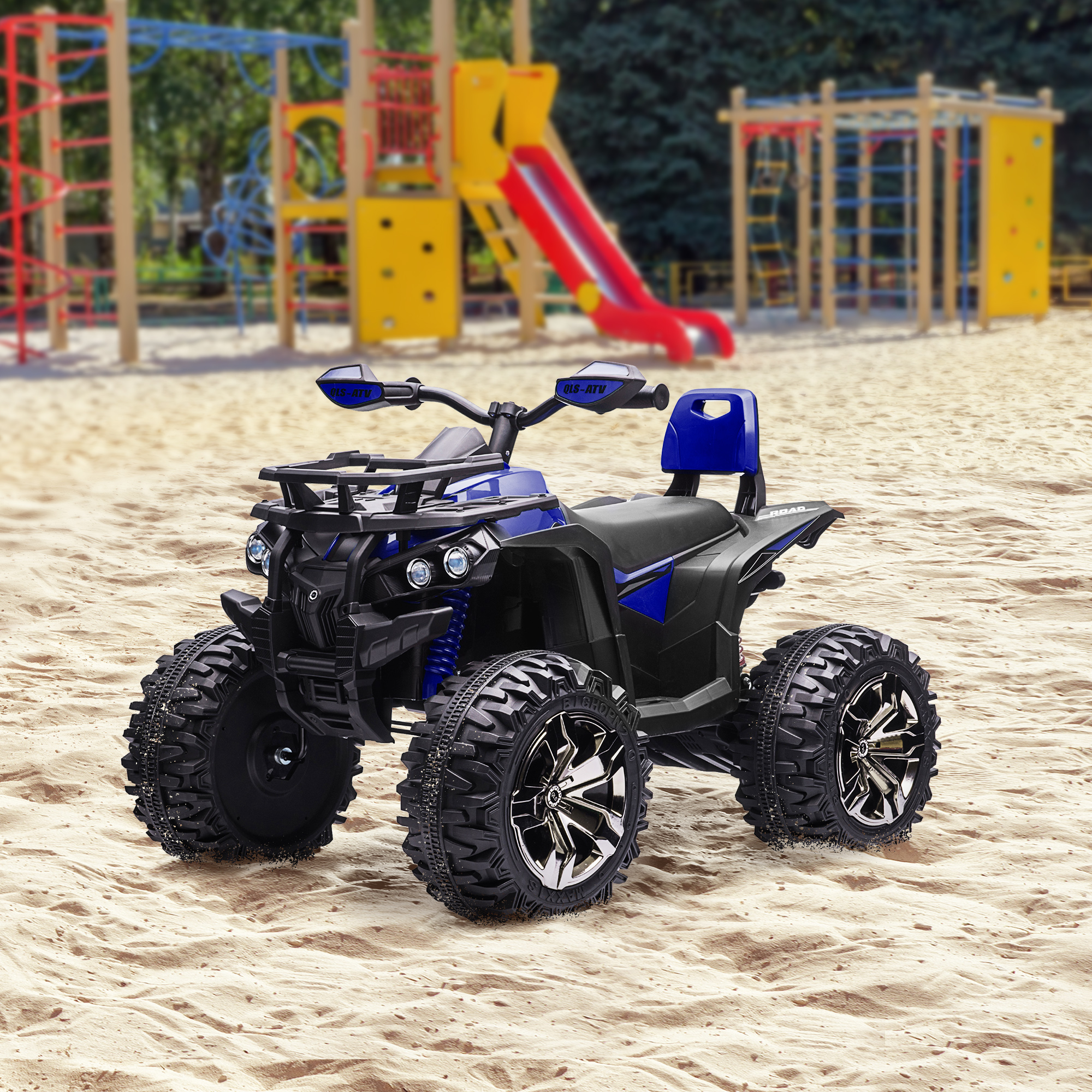 Un giocattolo ATV blu e nero sulla sabbia con un parco giochi sullo sfondo.