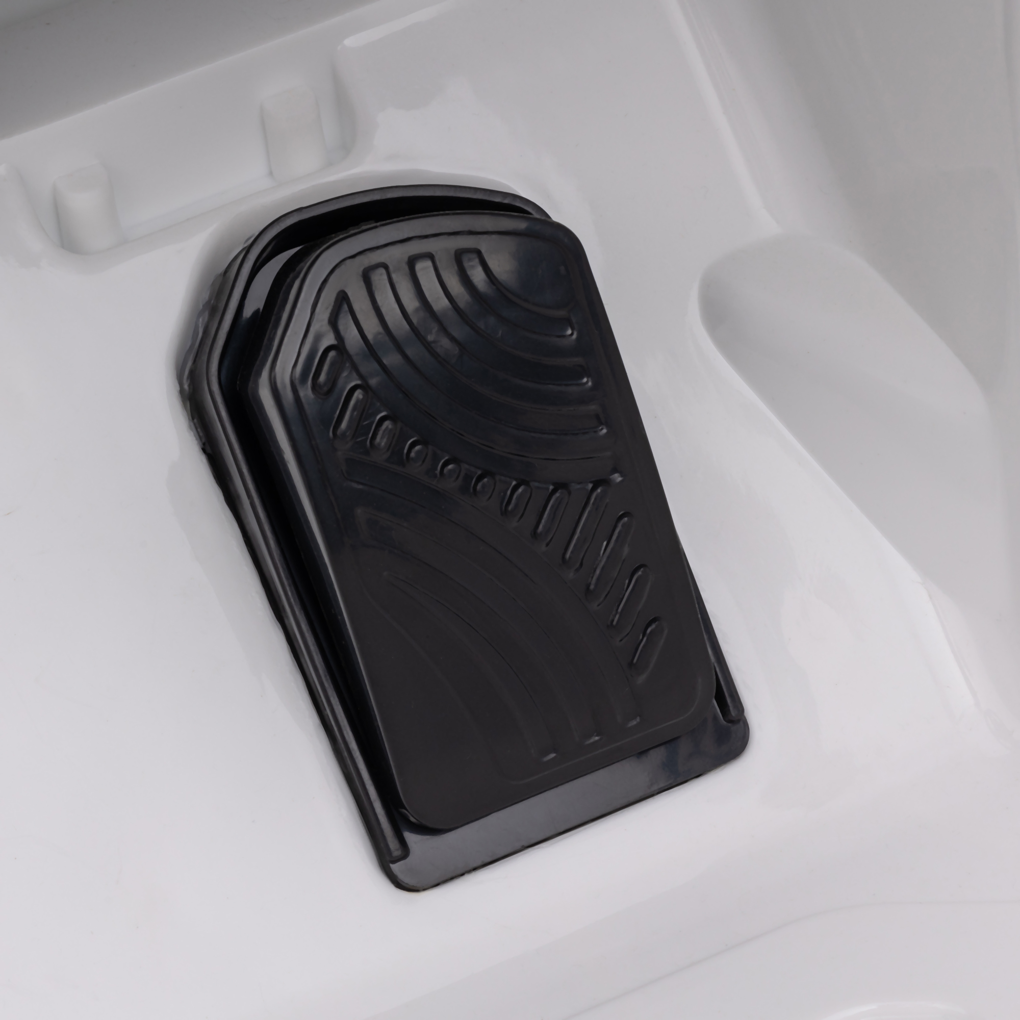 Primo piano di un pedale nero all'interno di un'auto giocattolo bianca.
