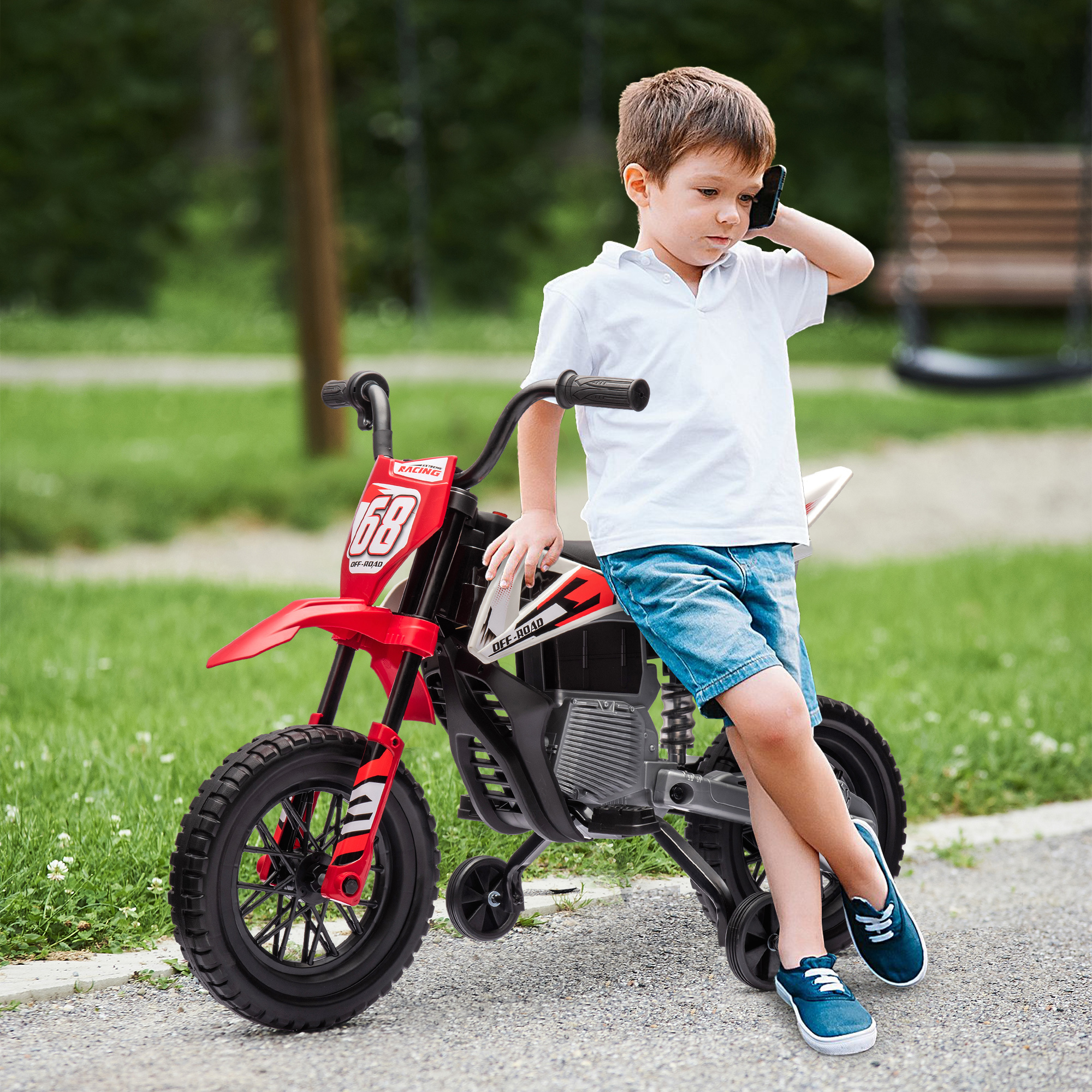 Ragazzo con moto giocattolo, parla al telefono. Moto rossa e nera, parcheggiata su strada.