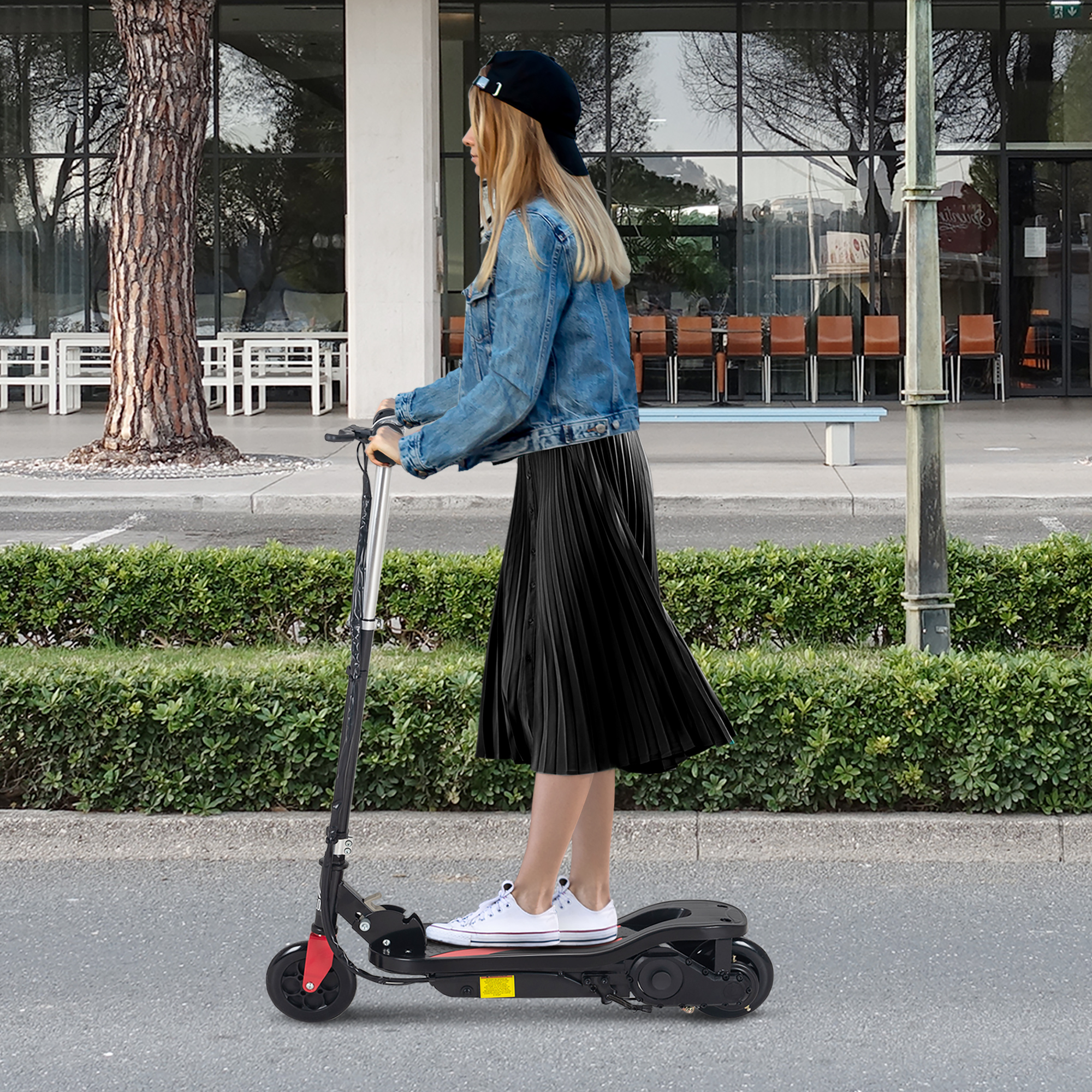 Donna che guida uno scooter elettrico nero, con giacca di jeans e gonna nera, su una strada.