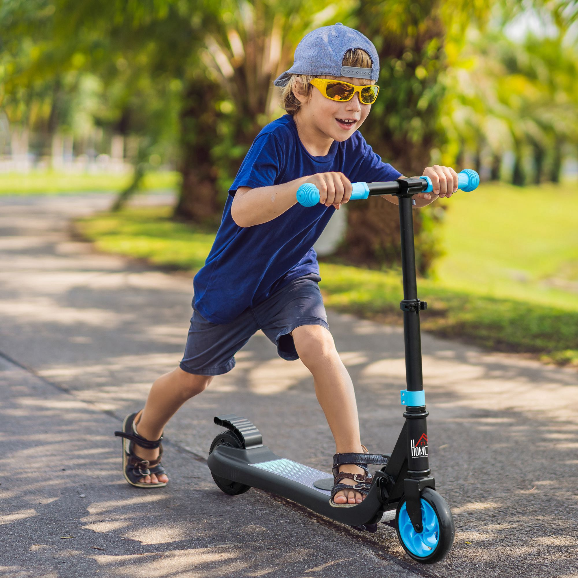 Un ragazzino su uno scooter, con cappellino e occhiali da sole, su un sentiero.