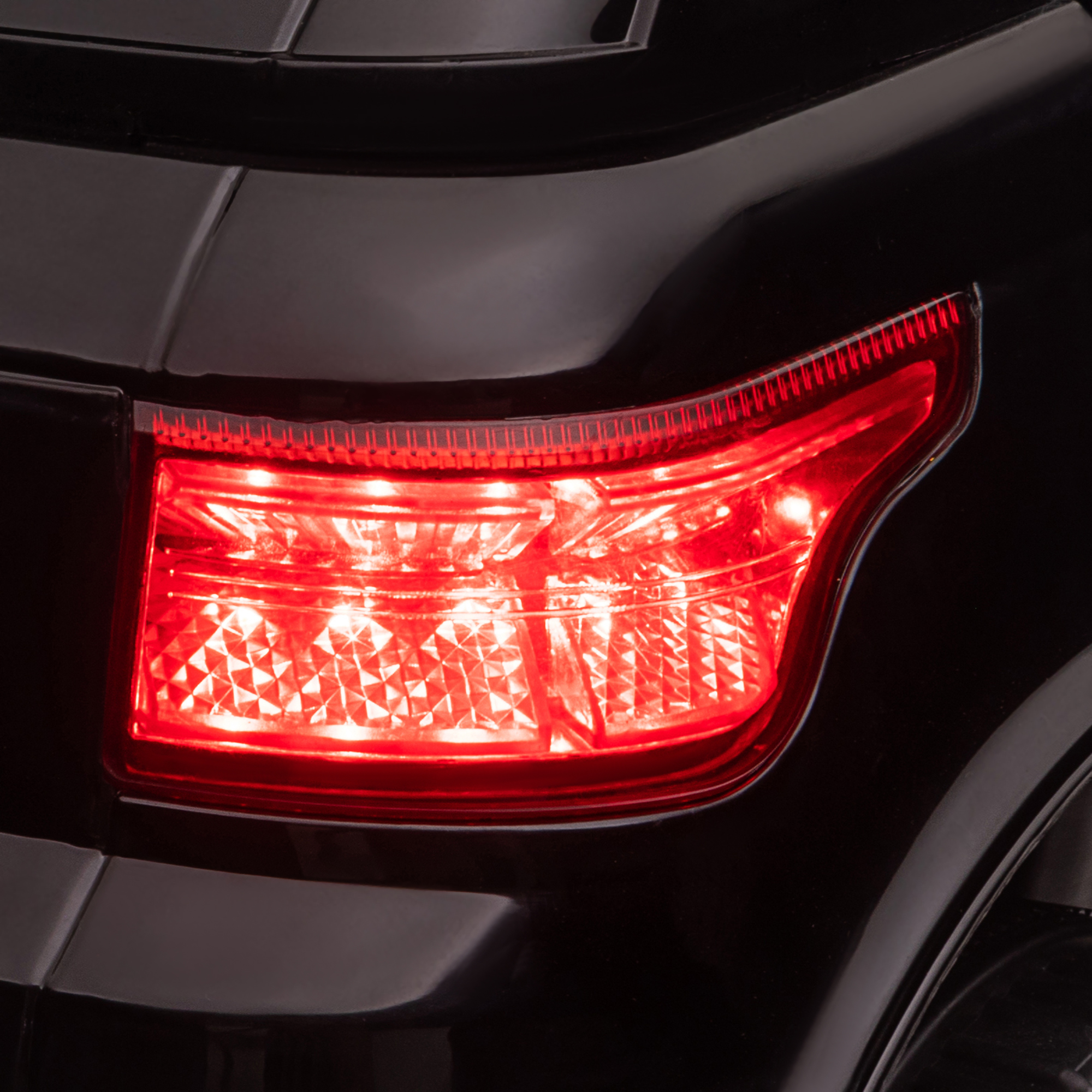Primo piano del fanale posteriore di un'auto nera, illuminato di rosso con LED luminosi.