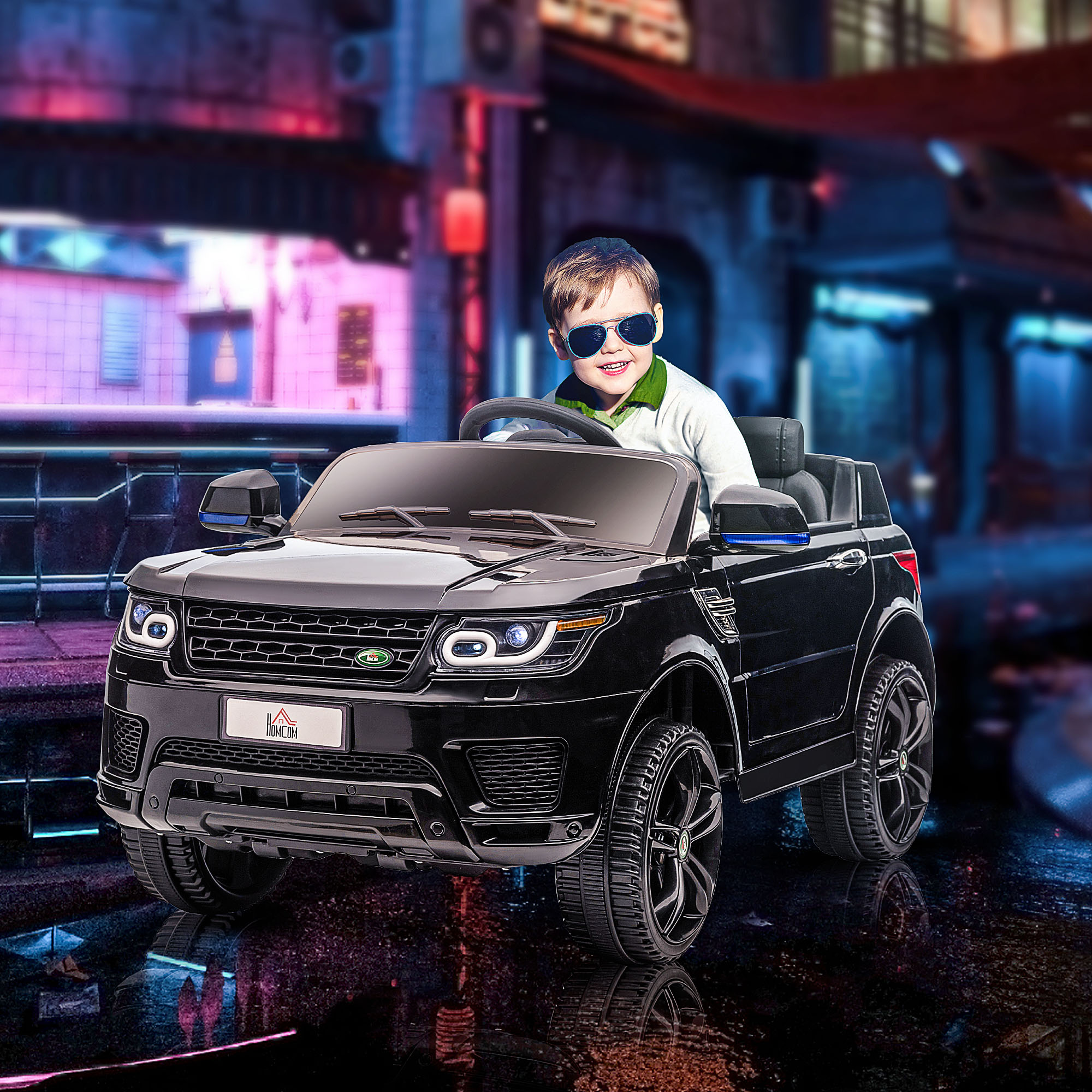 Un bambino con occhiali da sole guida un'auto giocattolo nera con sfondo di città.