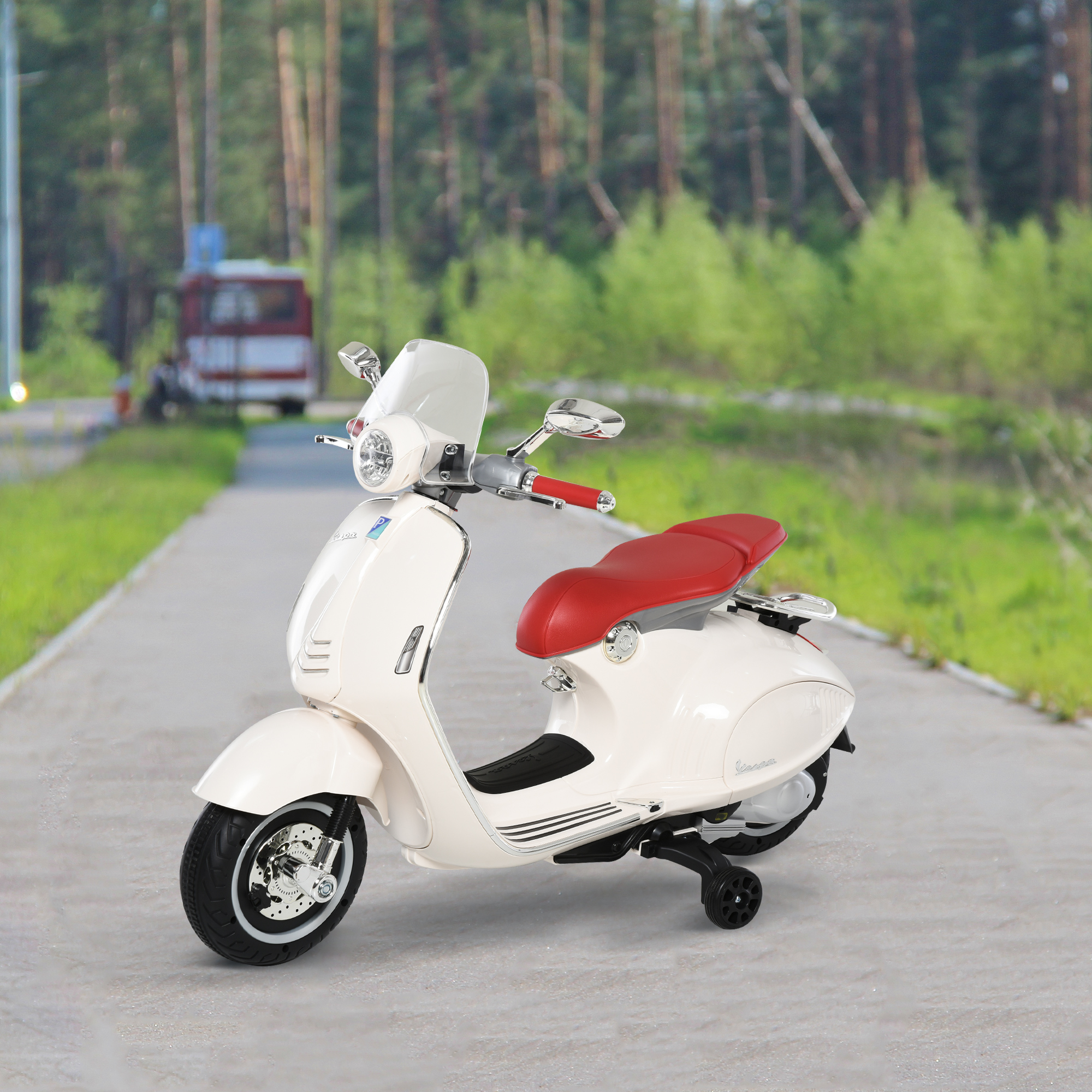 Scooter Vespa giocattolo bianco con sedile rosso su un sentiero lastricato. Sfondo: alberi e cielo.