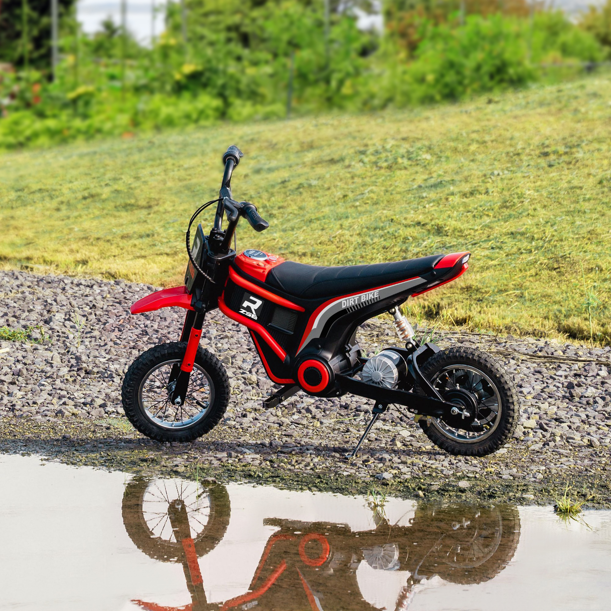 Moto da cross giocattolo rossa e nera con sedile nero, sull'erba con riflesso.