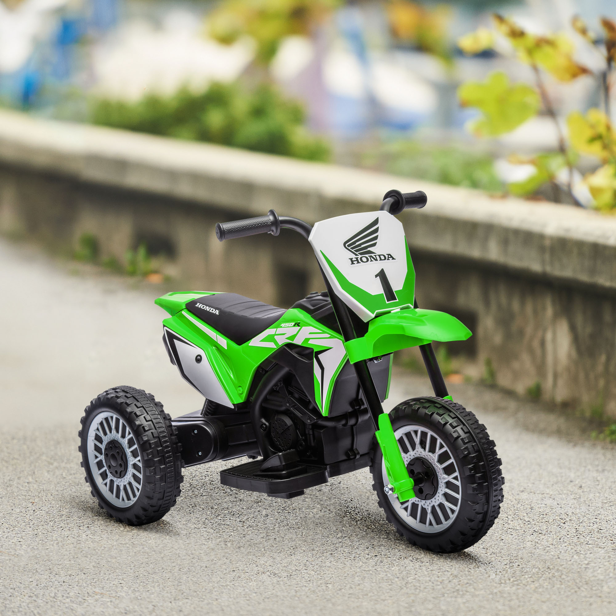 Moto giocattolo verde e bianca a tre ruote. C'è la parola Honda sopra.