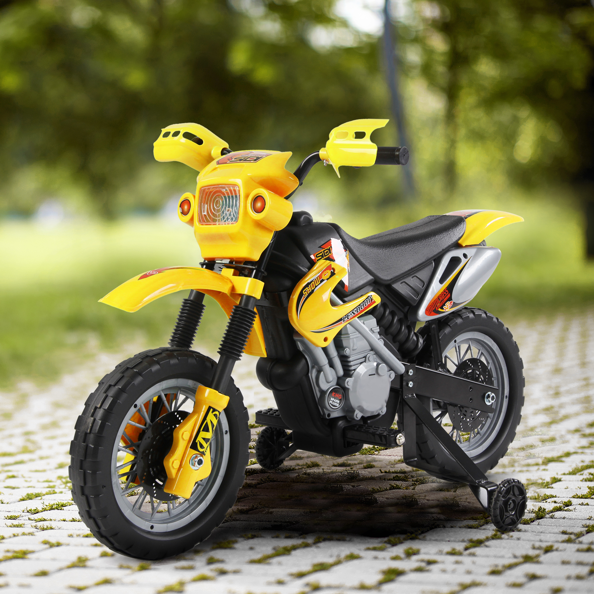 Moto giocattolo gialla su un sentiero pavimentato. Sfondo: pavimentazione e alberi.