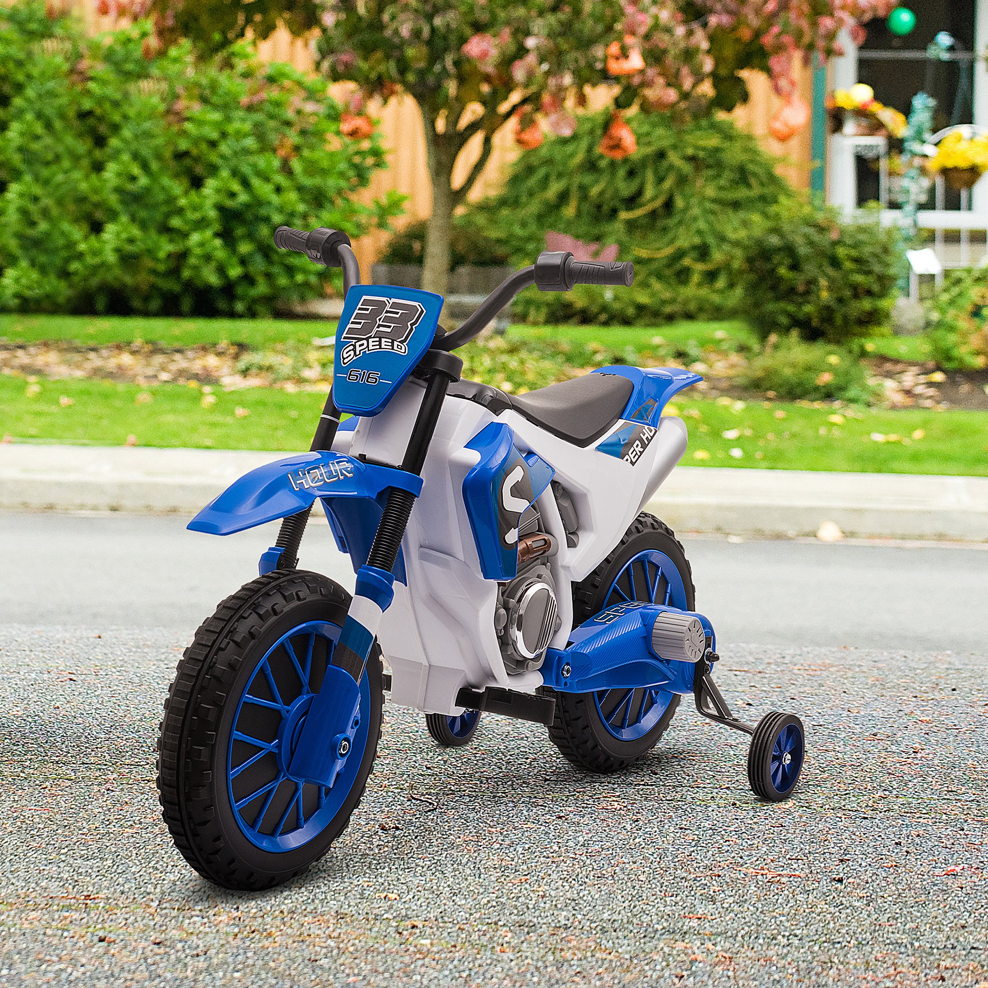 Moto giocattolo blu e bianca su una strada asfaltata. Lo sfondo ha un cortile verde e una casa.