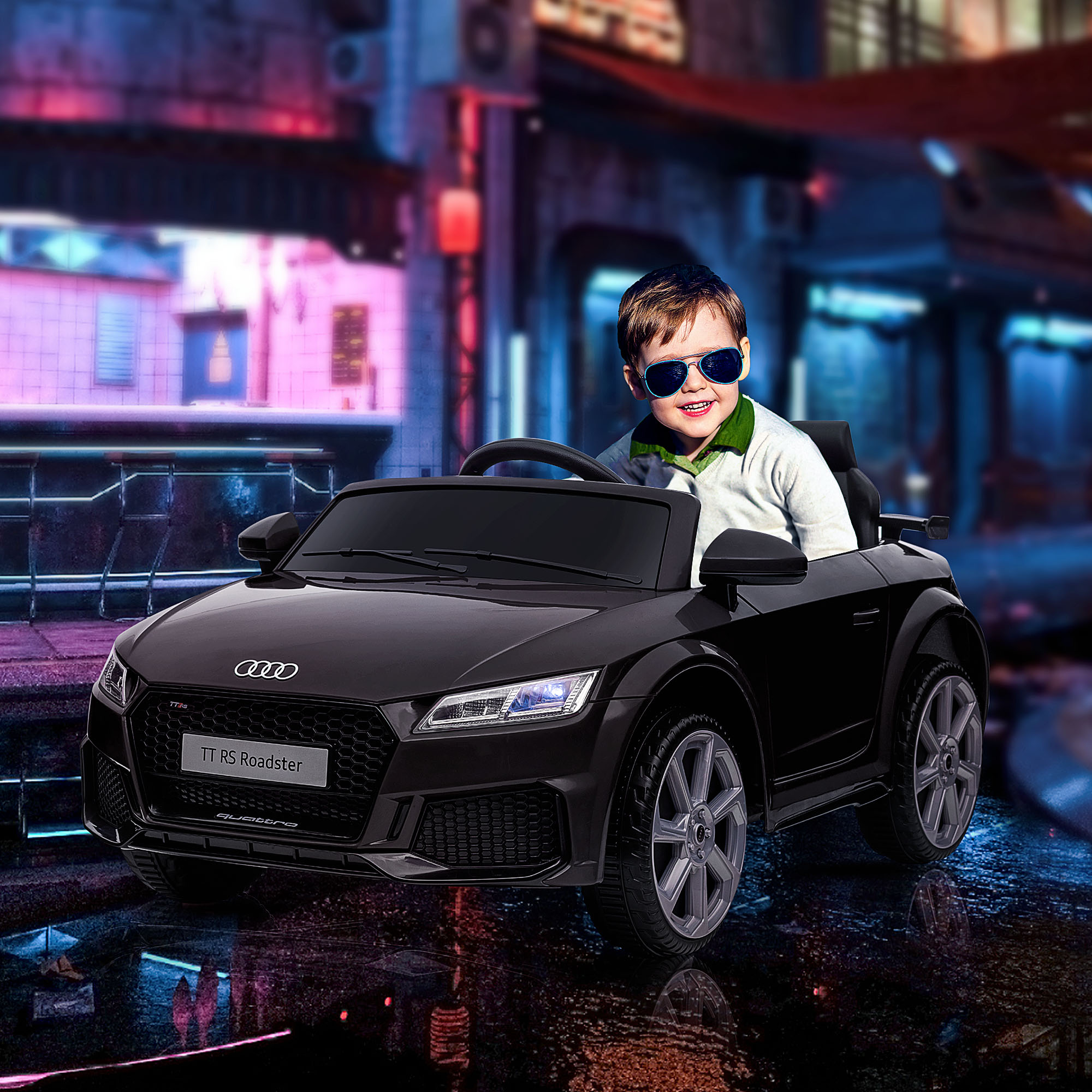 Un bambino in un'auto giocattolo nera Audi TT RS Roadster. Scena notturna con luci al neon.