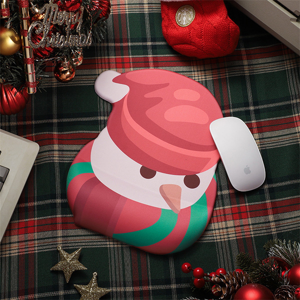 Ein schneemannförmiges Mousepad mit einer weißen Maus auf einer weihnachtlichen Oberfläche.