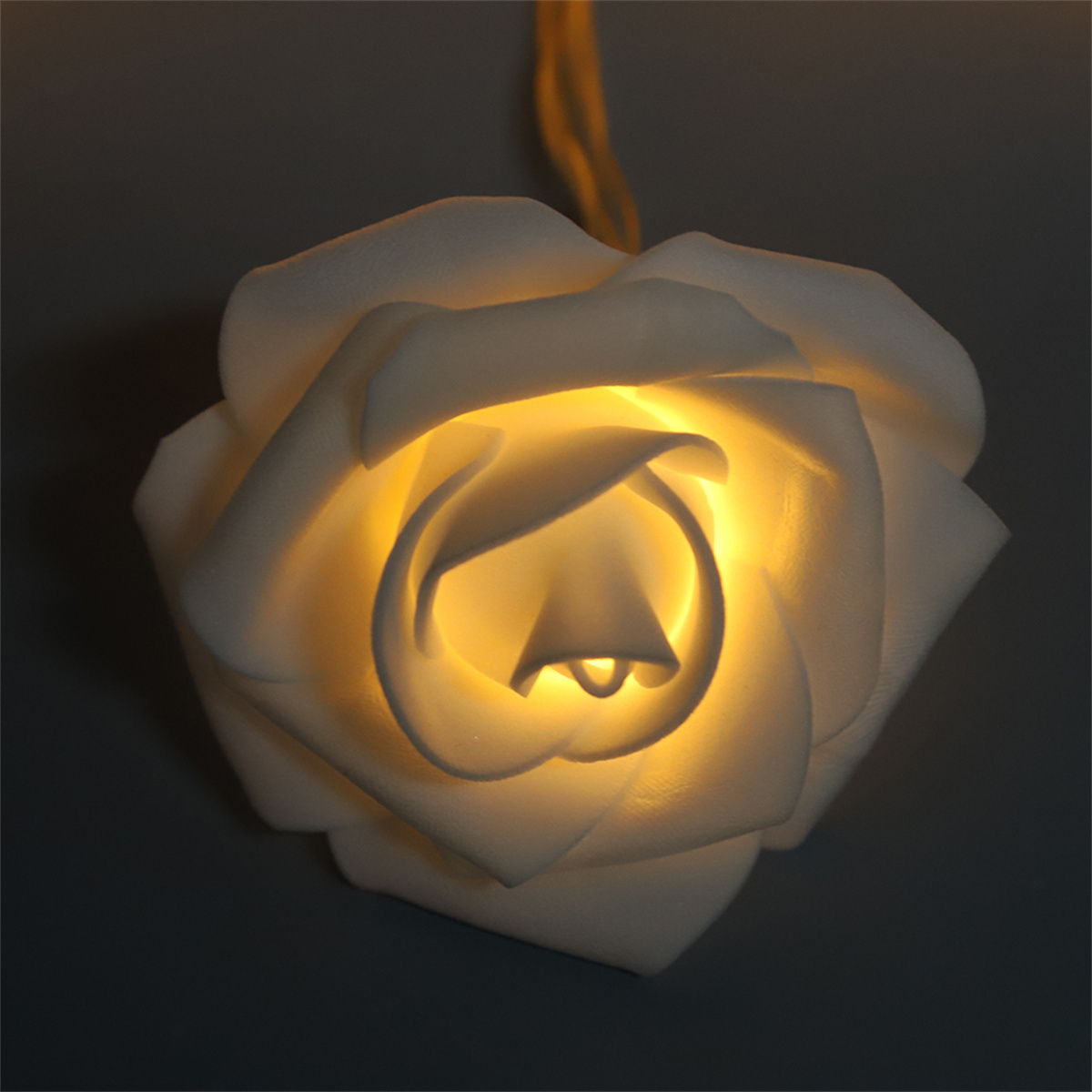 Eine weiße Rose mit leuchtendem Zentrum vor dunklem, grauem Hintergrund.