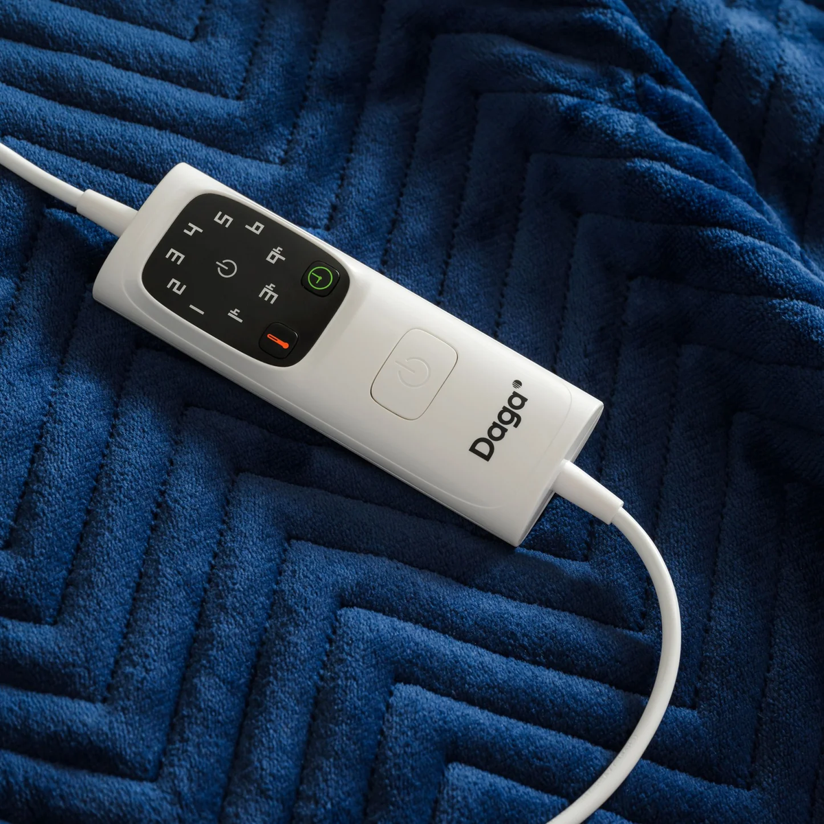 Un panel de control blanco en una manta azul estampada con un cable blanco.