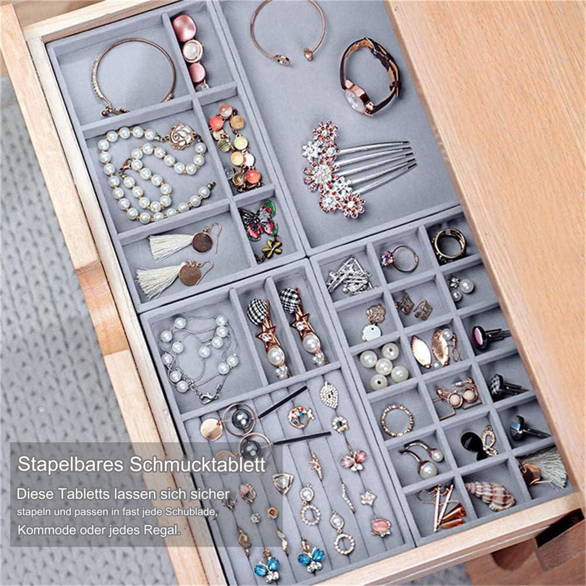 Ein Schmuckaufbewahrungsfach mit Fächern, die mit Schmuck gefüllt sind. Das Fach befindet sich in einer Holzkiste.