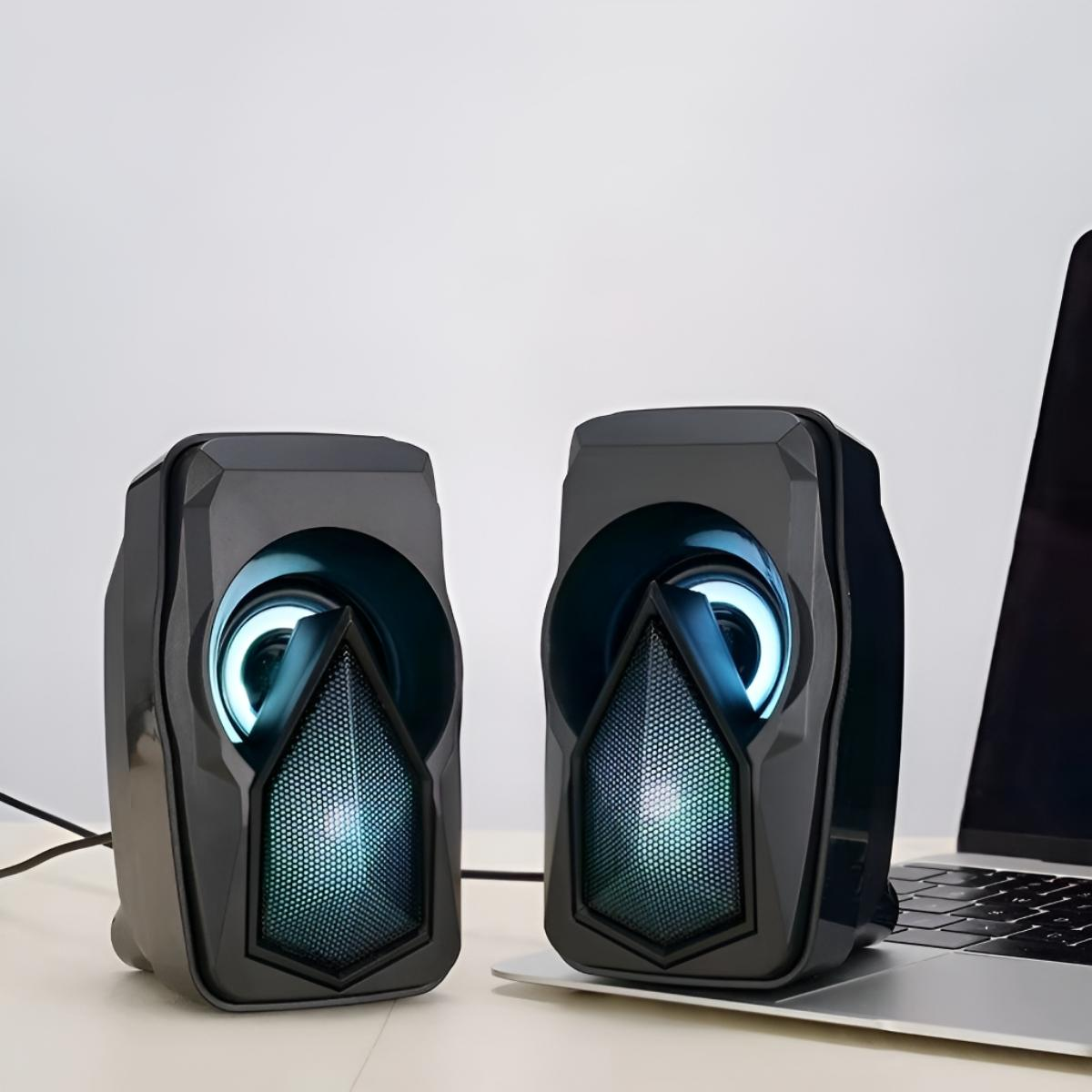 Zwei schwarze Computerlautsprecher mit einem beleuchteten Innenring, auf einem Laptop platziert.