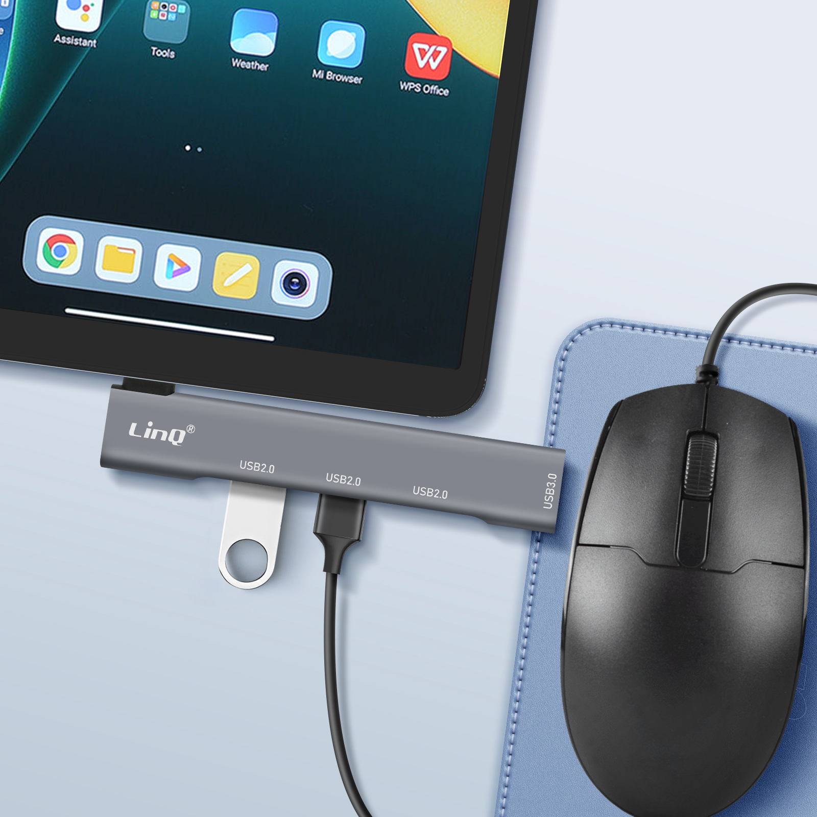 Une tablette connectée à un hub USB gris et une souris noire. Elle affiche des applications.