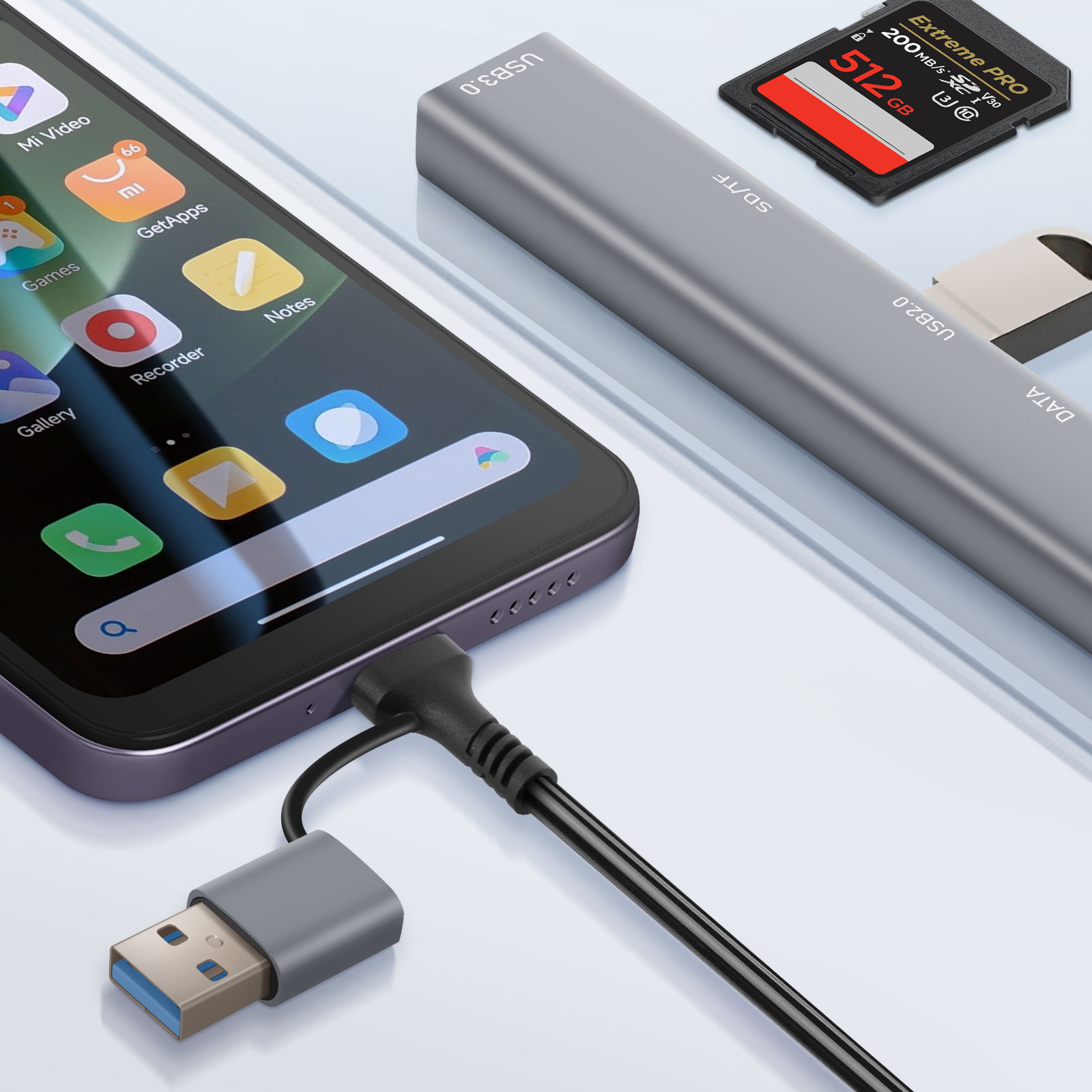 Smartphone connecté à un hub USB avec carte SD insérée et câble USB. Téléphone noir, hub gris.