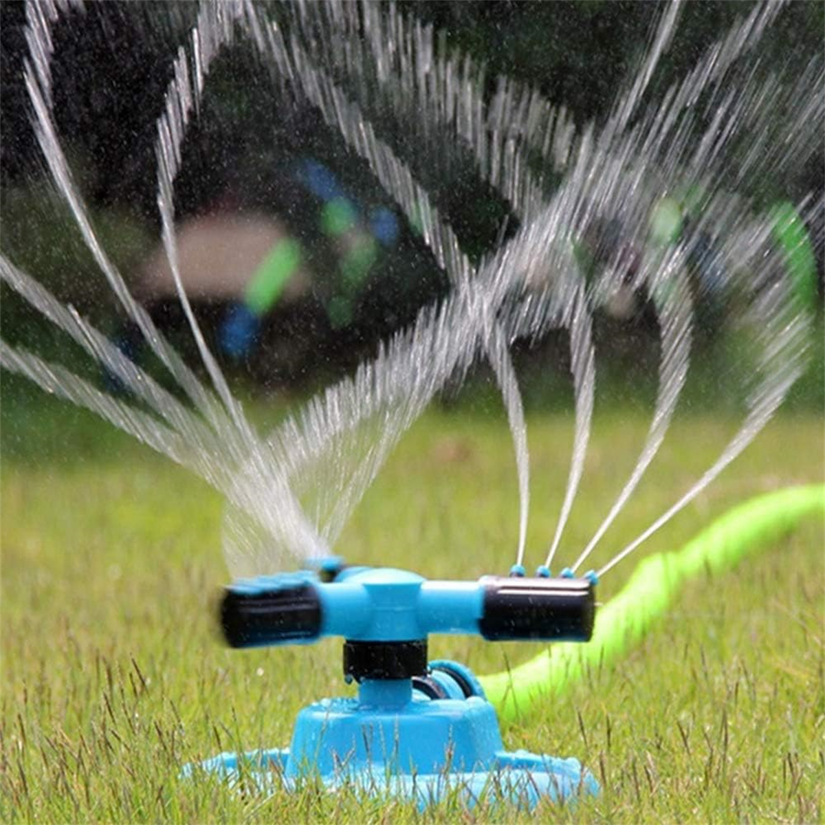 Ein blauer Rasensprenger sprüht Wasser auf grünes Gras.