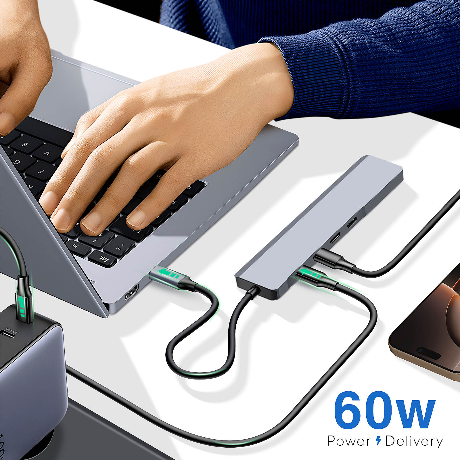Persona che utilizza un laptop collegato a un hub USB con più porte. Sono presenti anche un telefono e un caricatore.