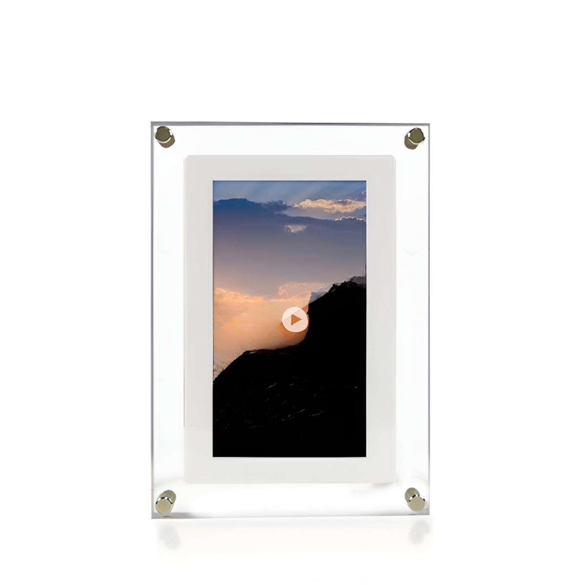 Ein gerahmtes Bild mit Sonnenuntergang über einer Bergkette. Der Rahmen ist klar, auf weißem Grund.