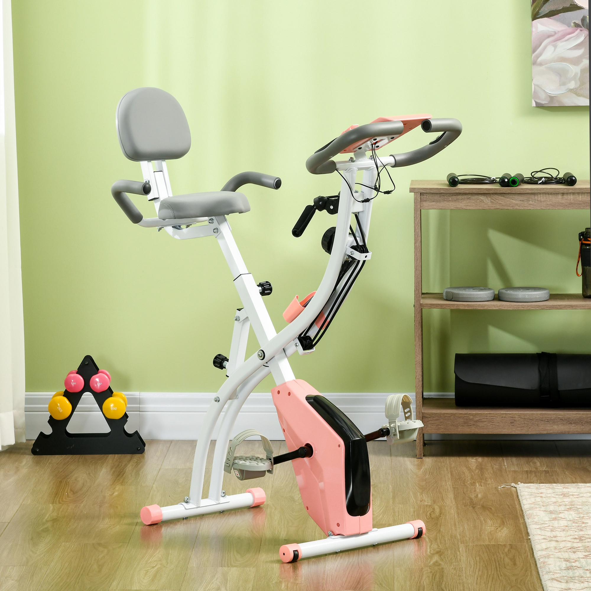 Una cyclette in una stanza, rosa e bianca, con parete verde e mensola in legno.