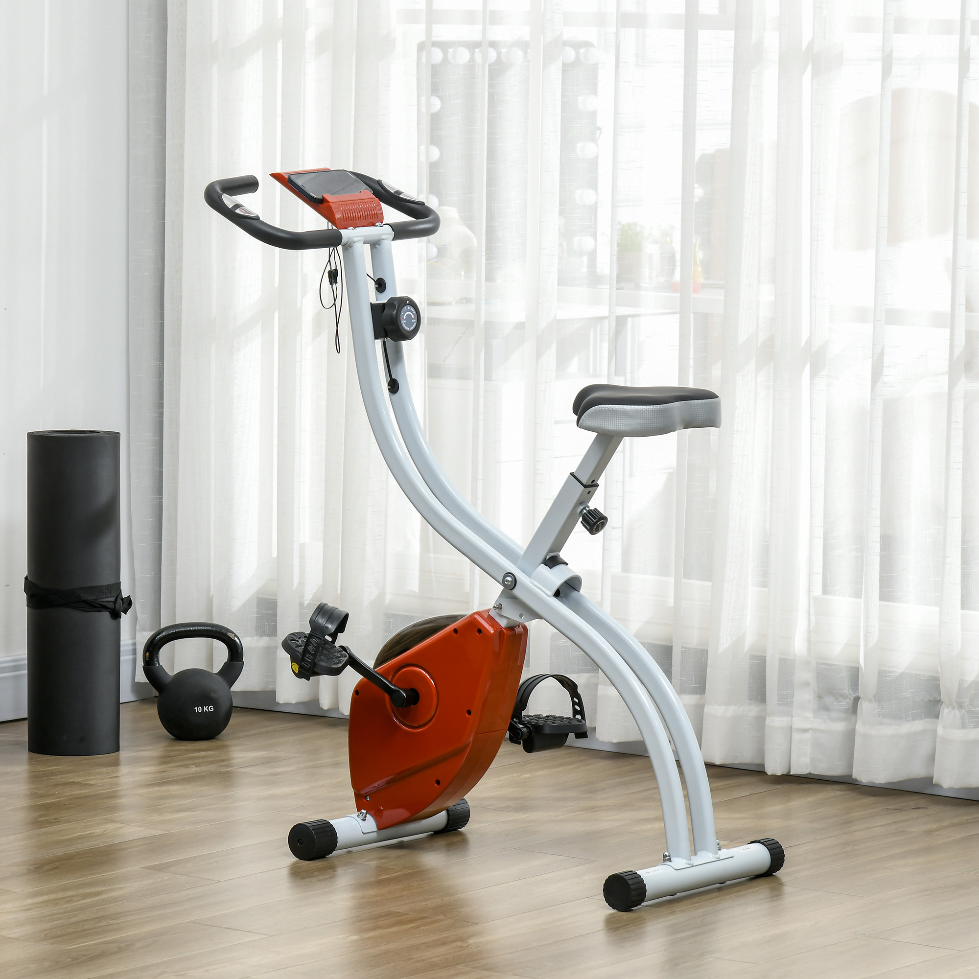 Bicicletta da spinning con telaio bianco, dettagli arancioni e maniglie nere. Include pesi e un tappetino yoga.