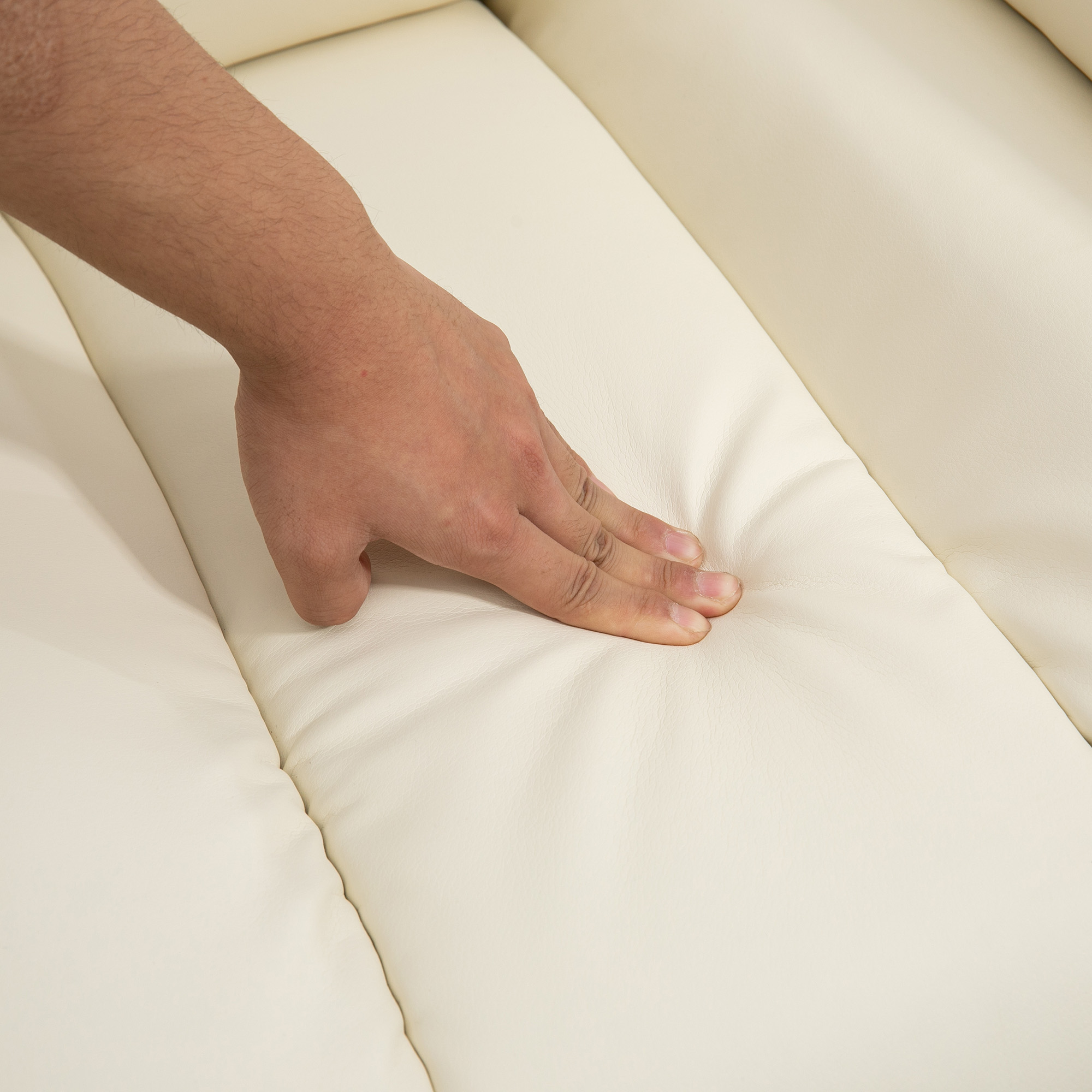 Eine Hand berührt eine weiße Ledercouch, Nahaufnahme.