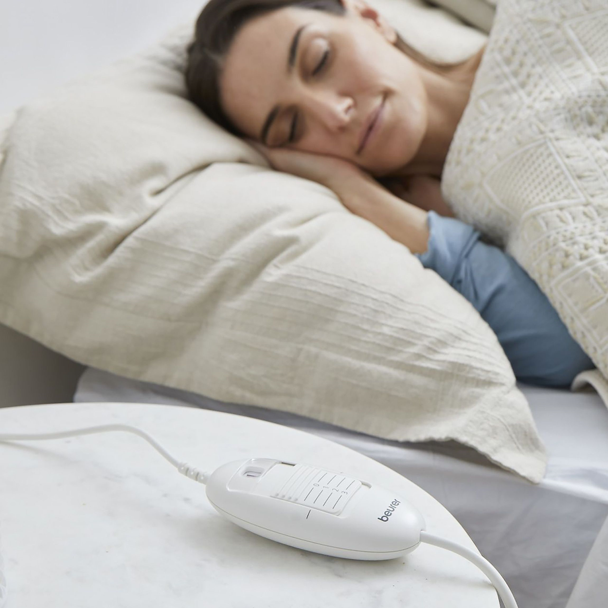 Donna che dorme a letto con un'unità di controllo bianca sul tavolo.