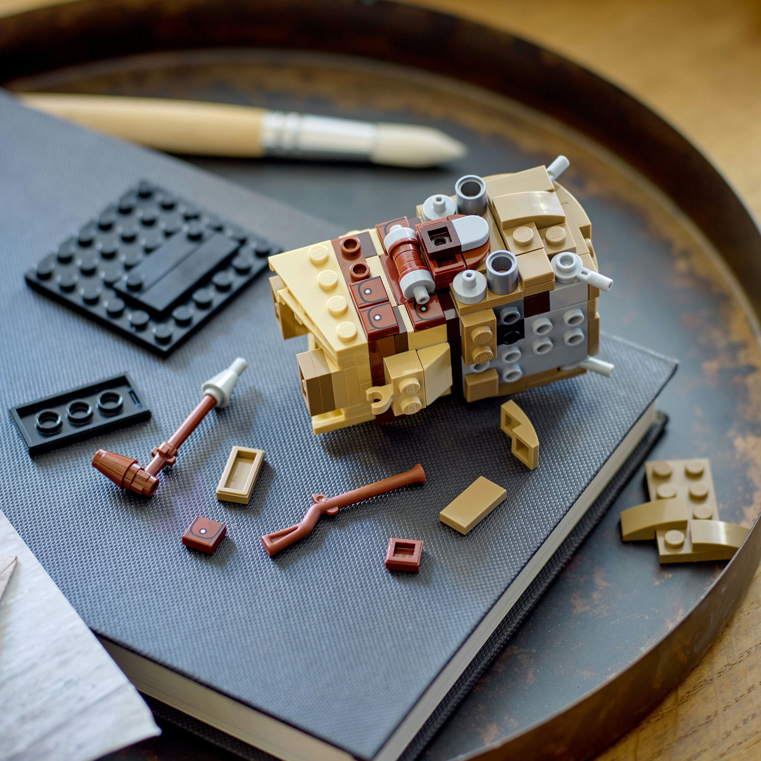 Ein zerlegtes Lego-Modell auf einem Buch mit Werkzeugen und zusätzlichen Steinen.