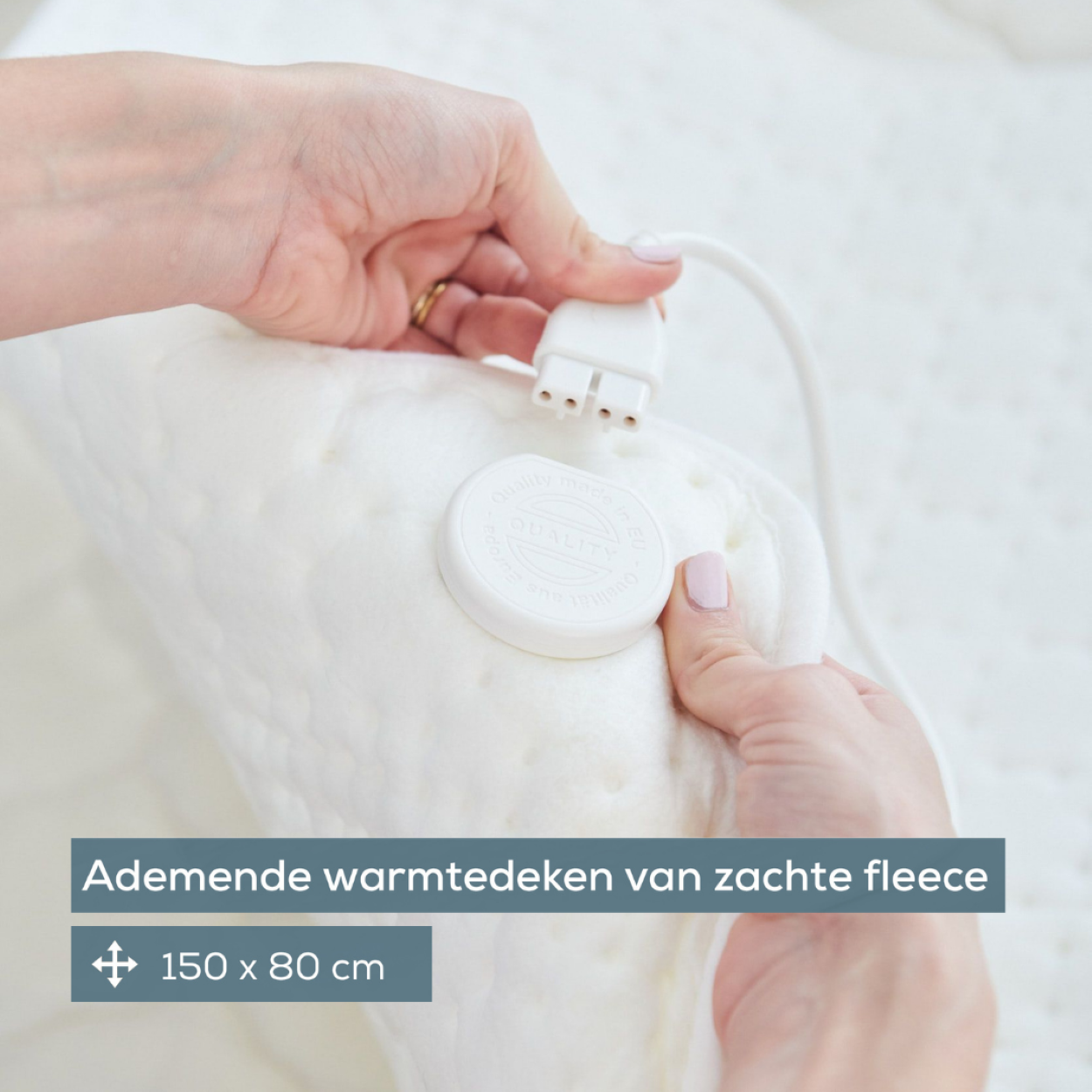 Nahaufnahme einer weißen elektrischen Heizdecke mit Netzkabel und Bedienelementen, rosa Nagellack.