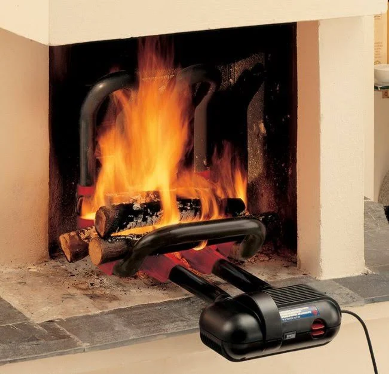 Caminetto con legno che brucia e fiamme. Un riscaldatore elettrico nero è in primo piano.