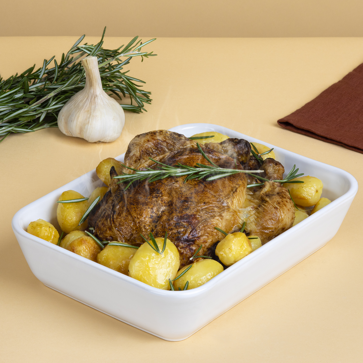 Pollo arrosto e patate in una pirofila bianca, su sfondo pesca.