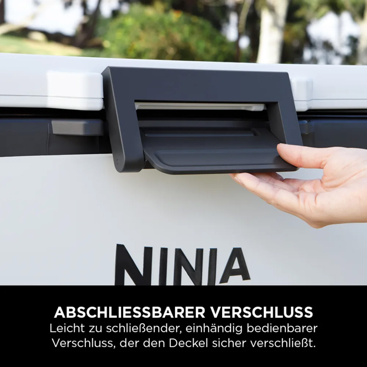 Ręka otwiera czarną zatrzask na białej chłodziarce, z napisem 'NINJA' w czerni.