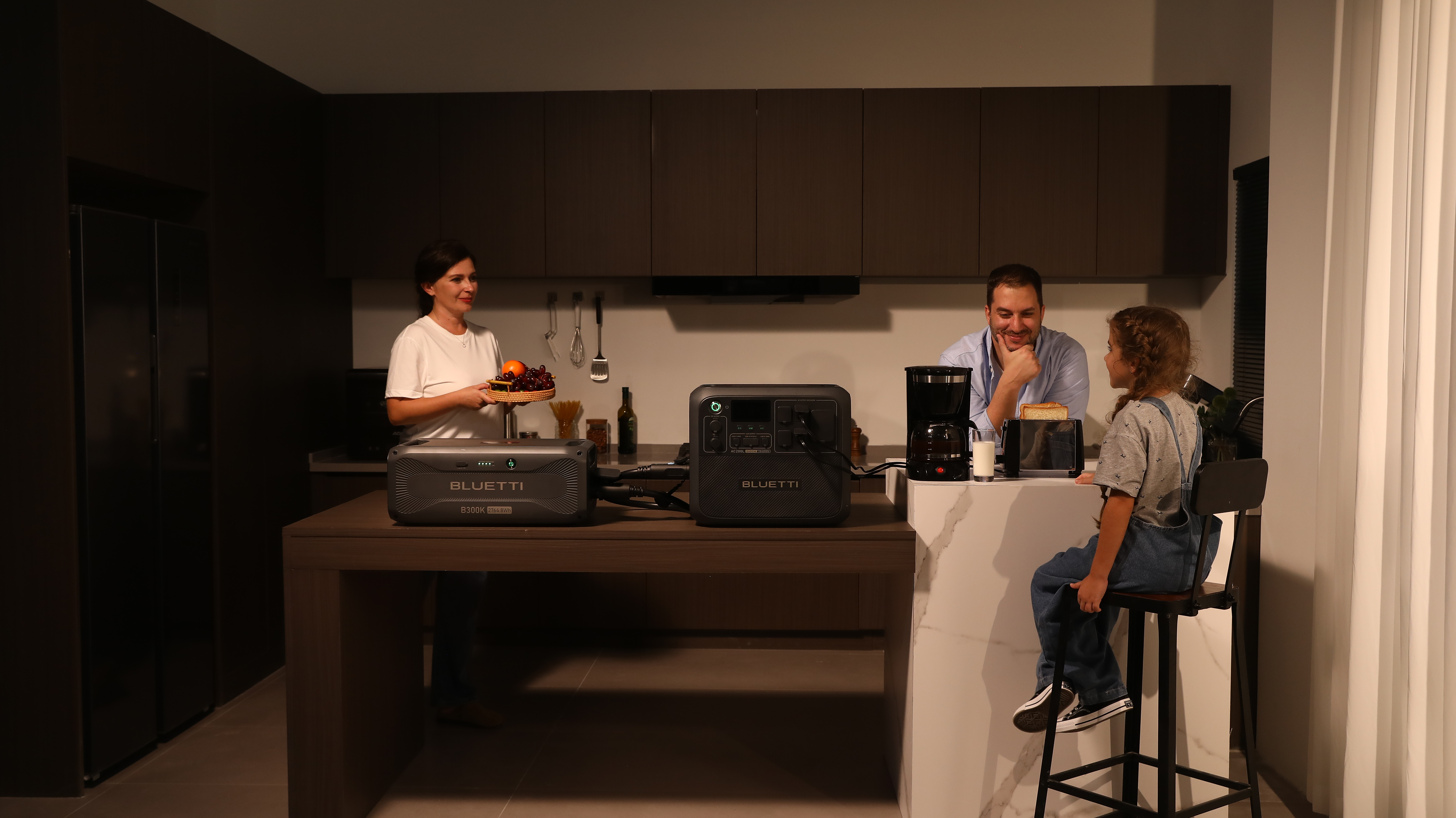 Rodzina w kuchni. Kobieta z owocami, mężczyzna i dziewczynka. Elektrownia na blacie.