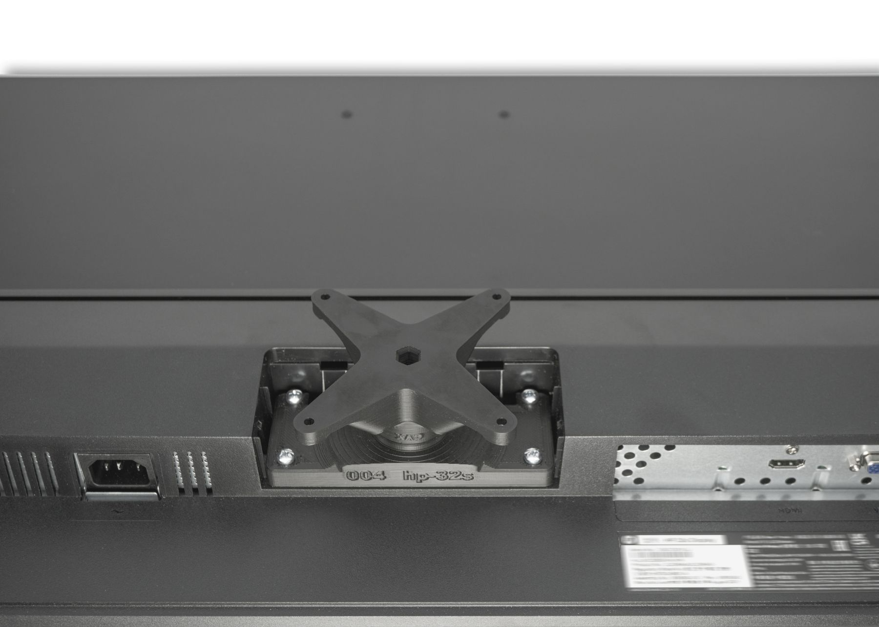 Rückseite eines schwarzen Monitors mit angebrachter Halterung. Anschlüsse und Ports sind sichtbar.