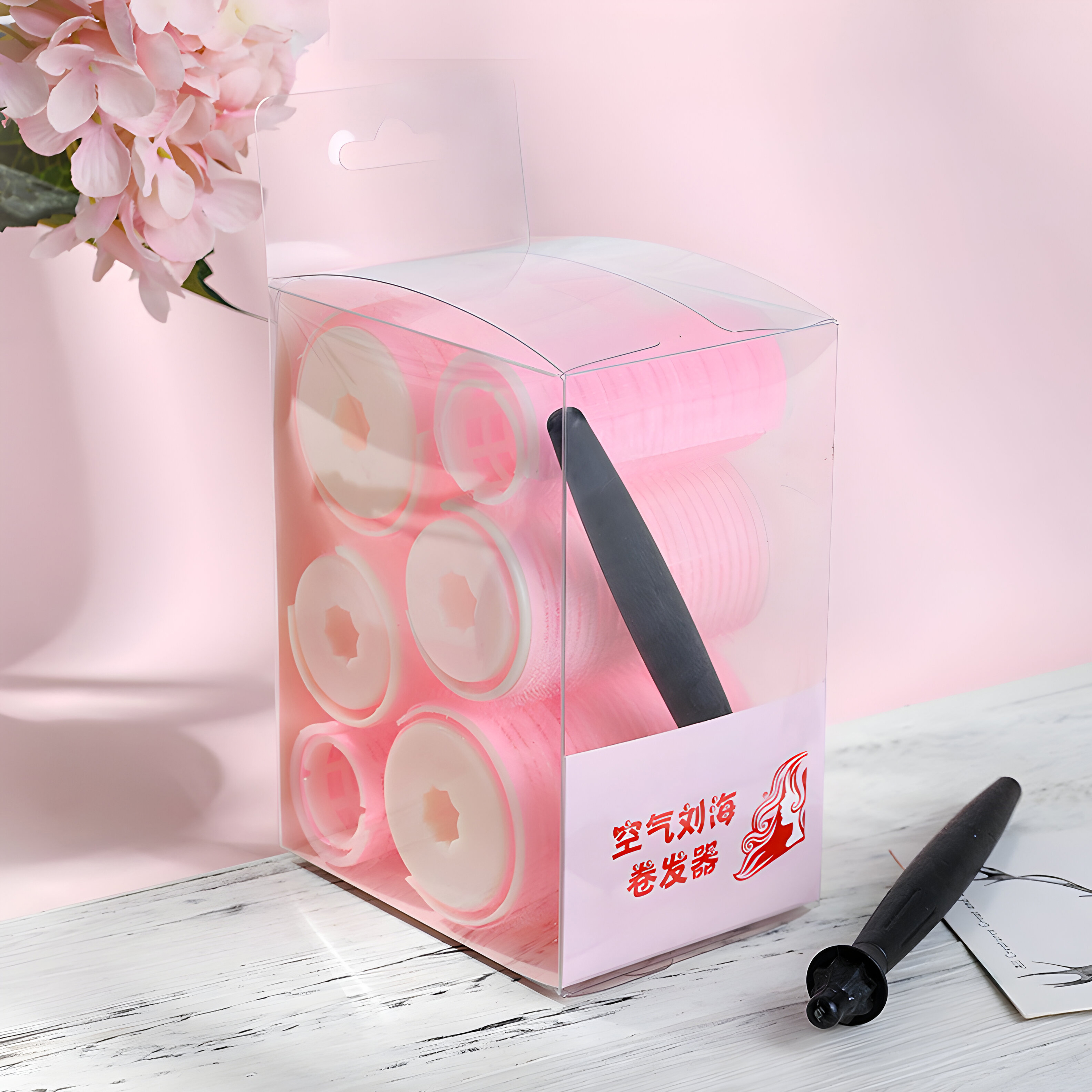 Rosa Haarroller in einer durchsichtigen Box, schwarzer Applikator.