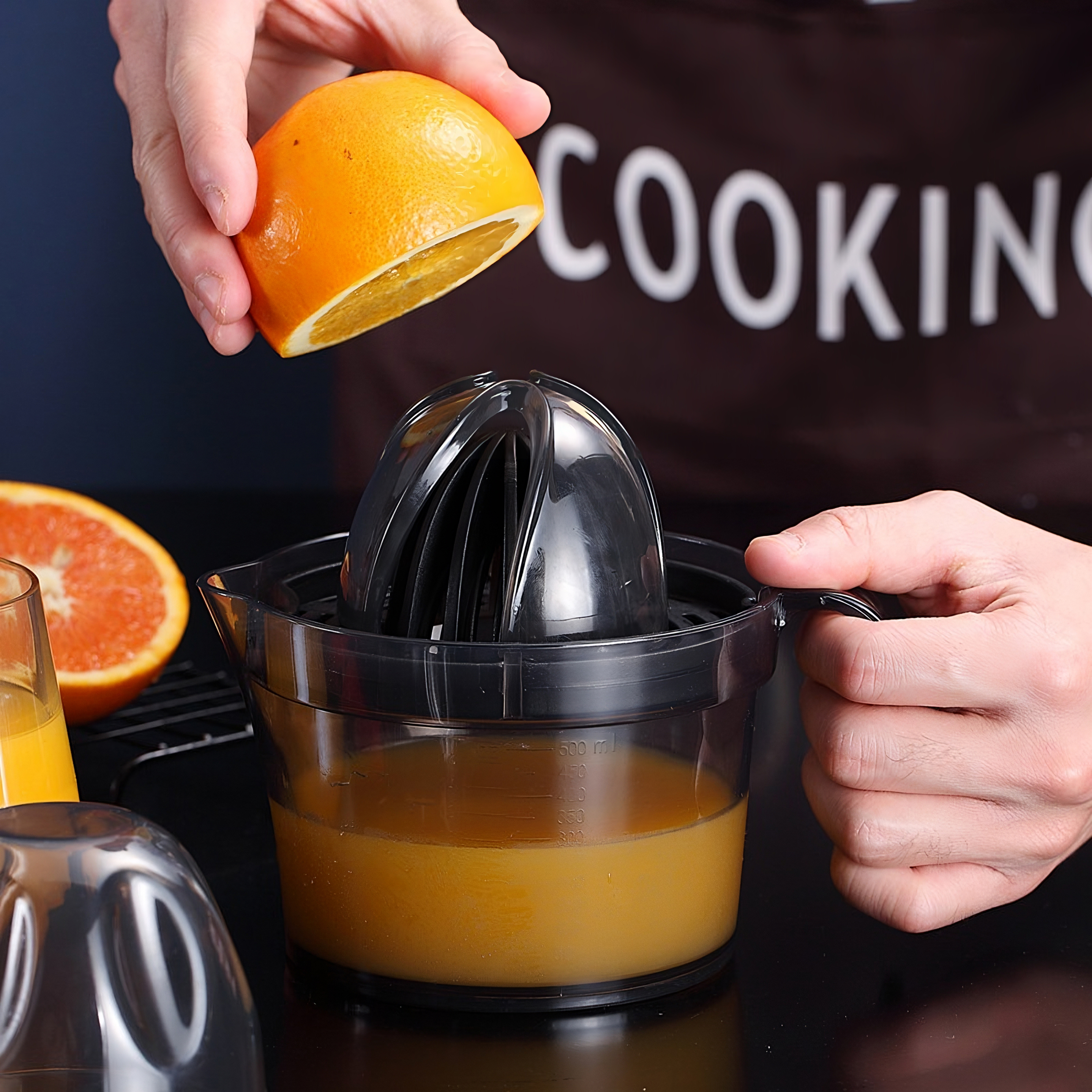 Eine Person presst eine Orange mit einem schwarzen Entsafter, Saft im Behälter.