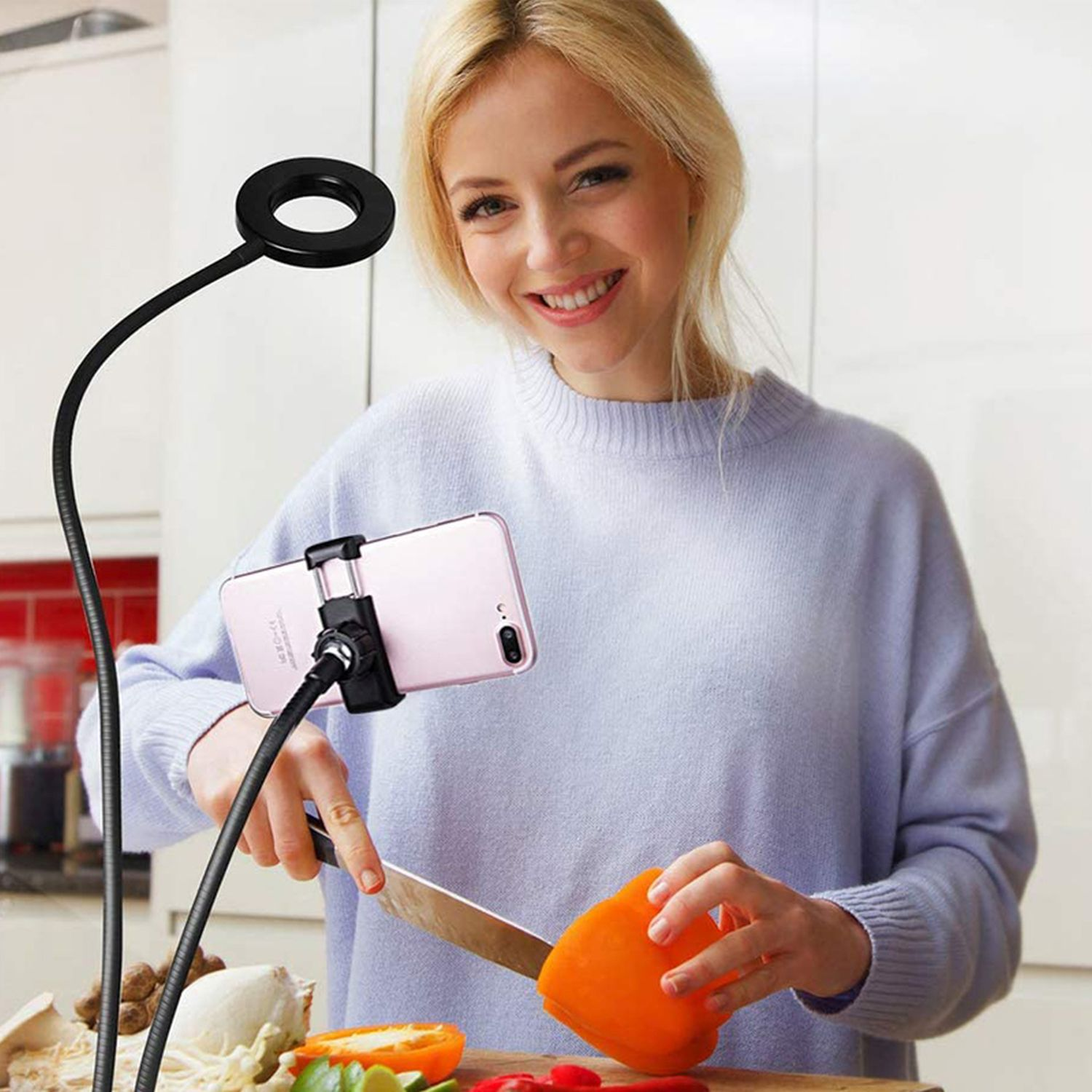 Eine Frau mit Ringlicht schneidet eine Orange, während sie sich mit dem Telefon aufnimmt.