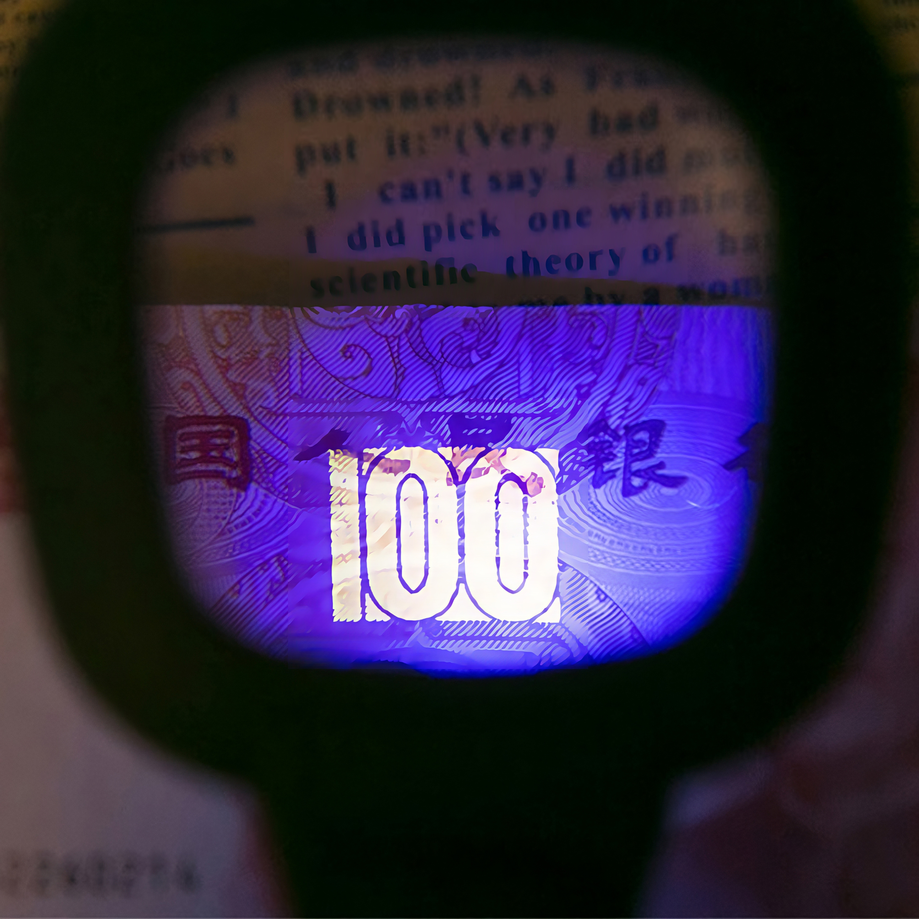 Eine Lupe beleuchtet die Zahl 100 auf einer Banknote unter UV-Licht.