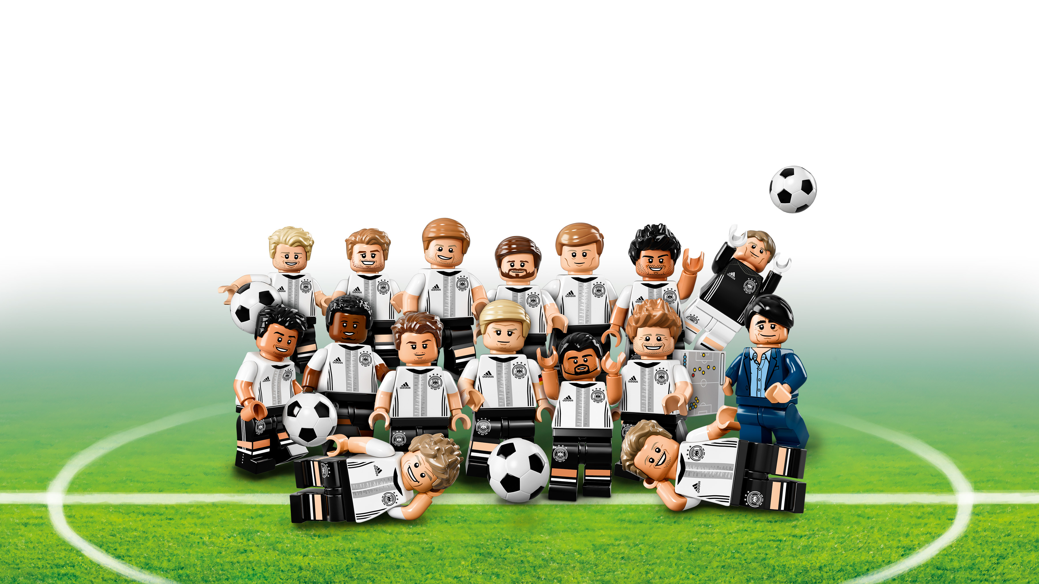 Giocatori di calcio Lego con maglie bianche e nere su un campo verde.