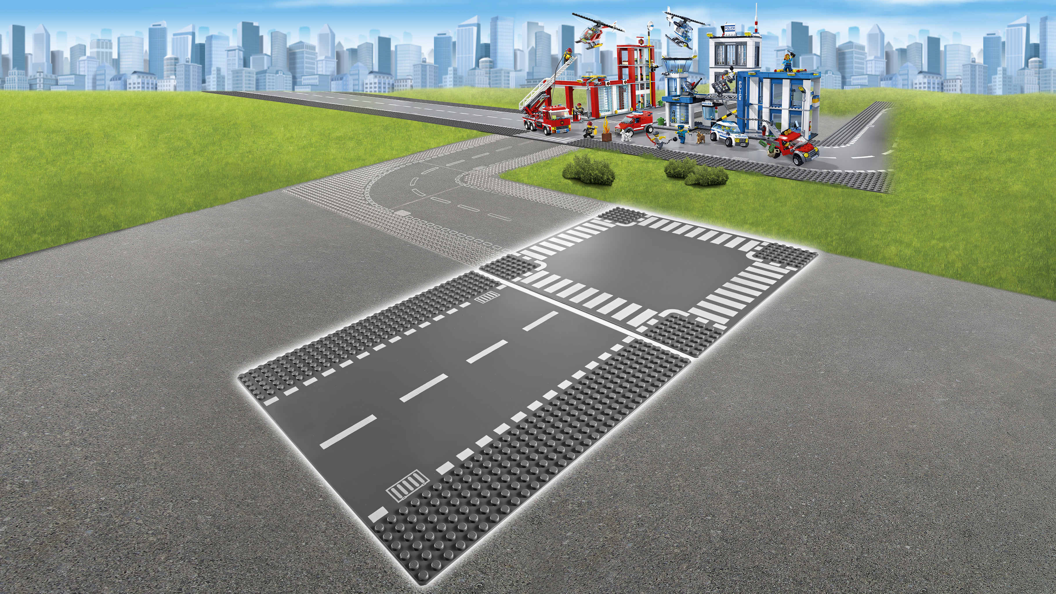 Lego City yol tabanı, yollar, binalar ve arka planda yeşil çim alanı.