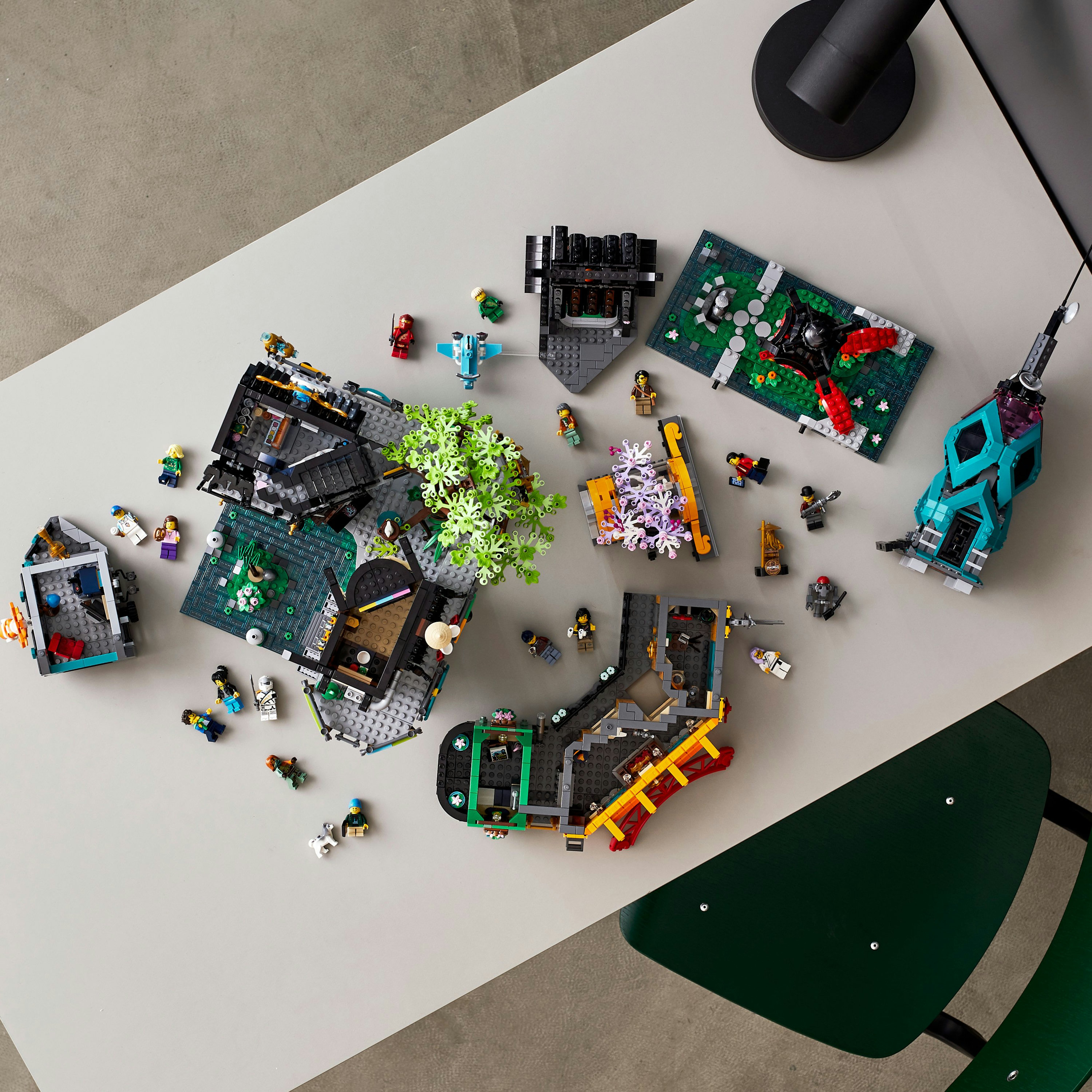 Zestawy Lego na stole. Różne konstrukcje i minifigurki są rozrzucone.