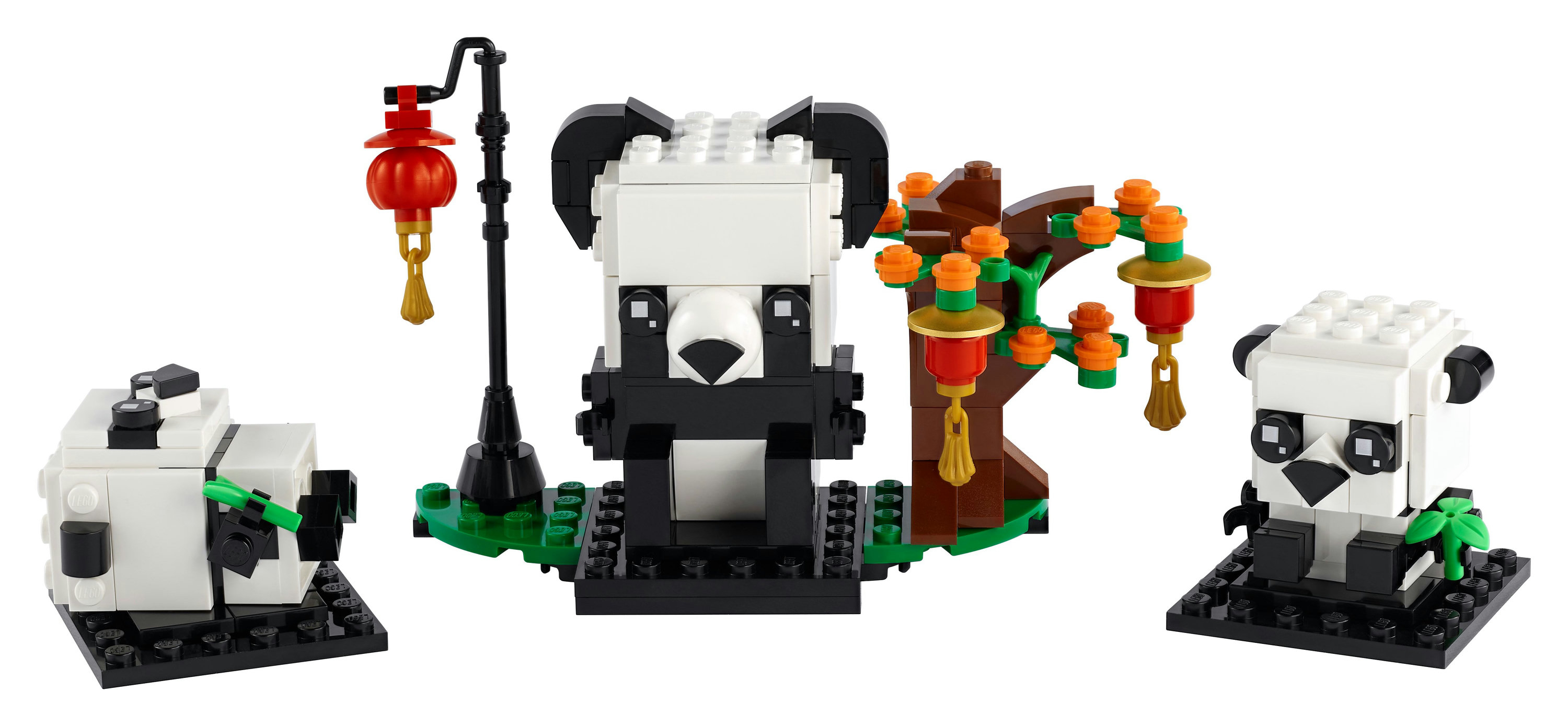 Set LEGO di tre panda, un albero e una lanterna su base nera, con sfondo bianco.