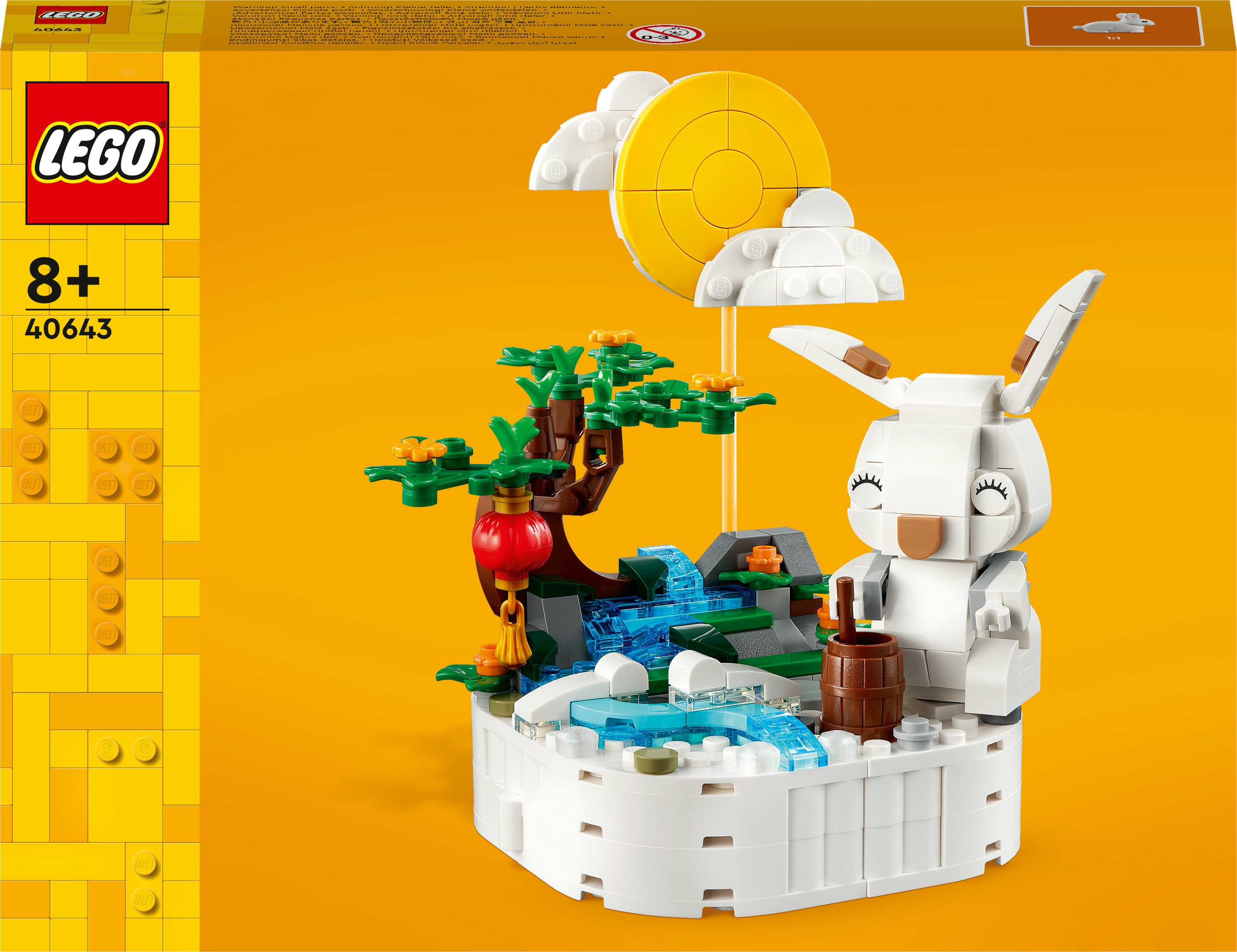 Un set Lego con un coniglio, una cascata, una luna e un albero su sfondo giallo.