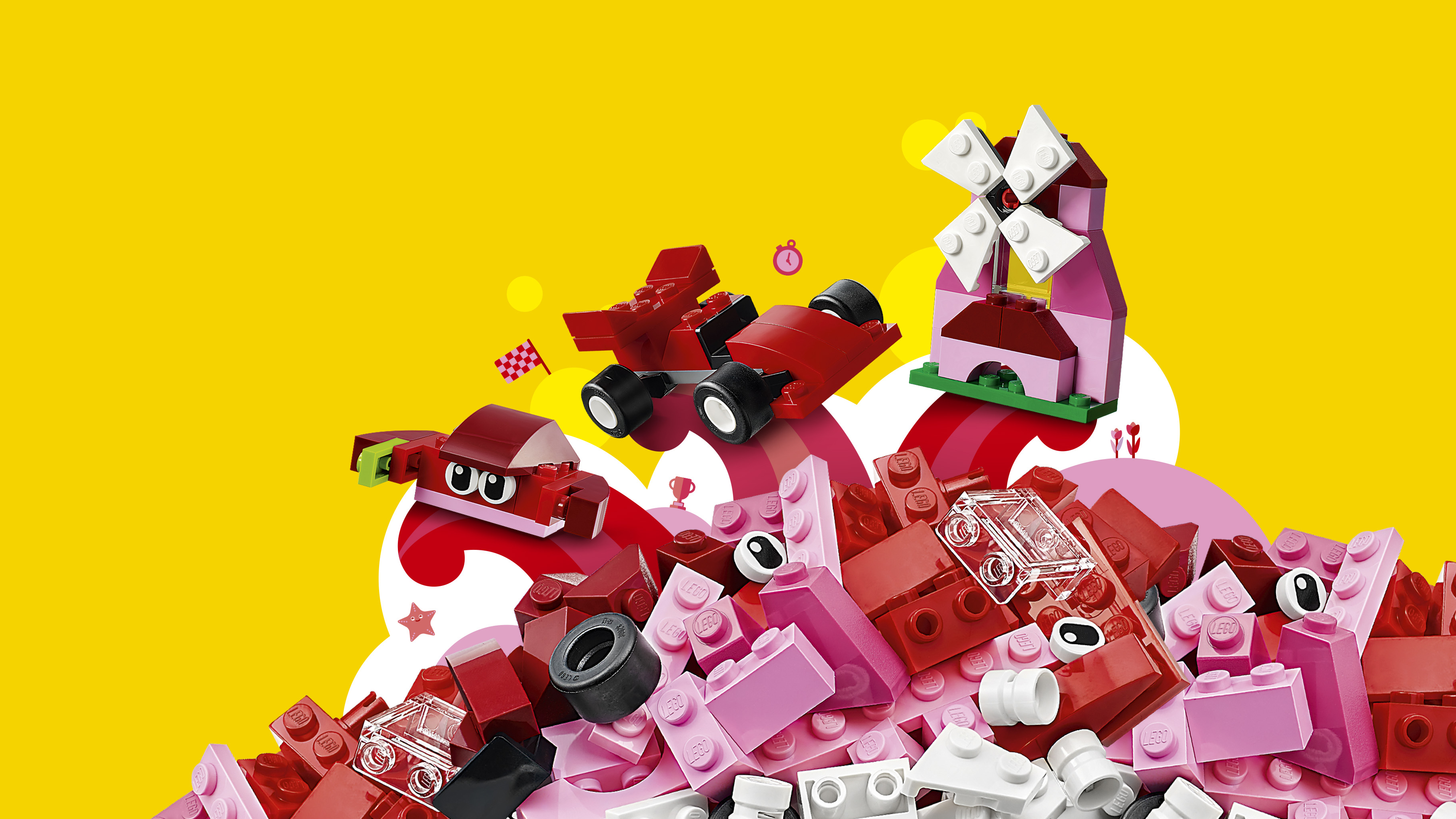 Set Lego con mattoncini rossi e rosa, auto da corsa e un mulino, tutto su sfondo giallo.