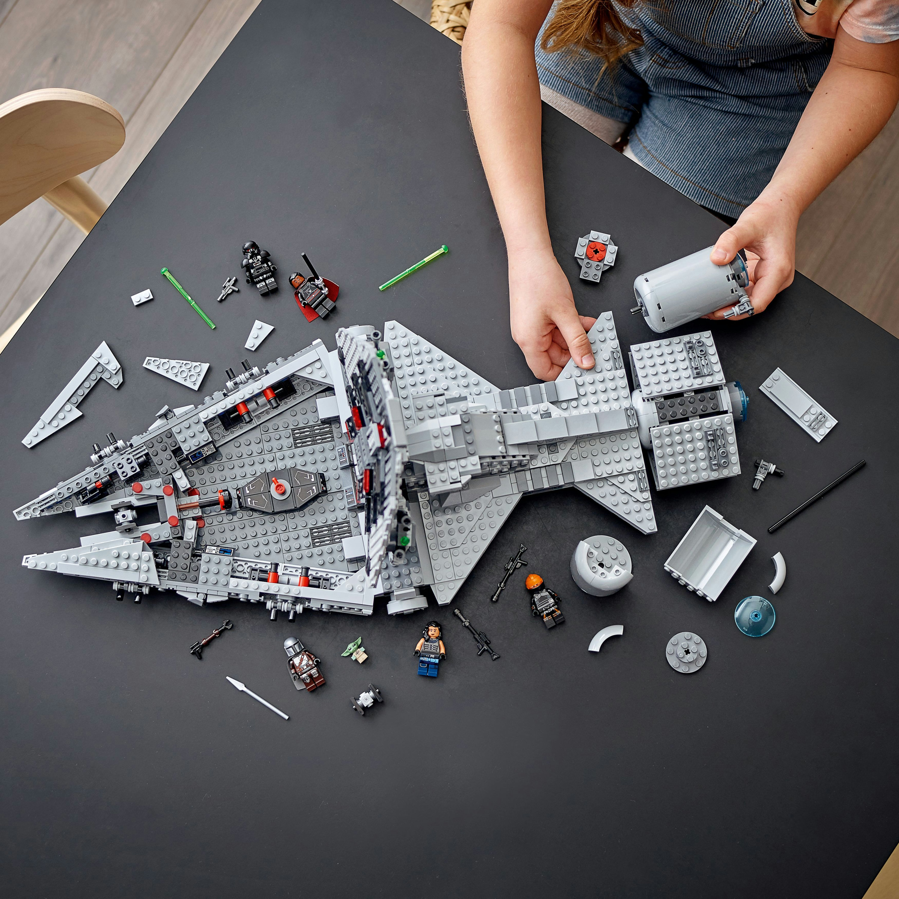 Bir LEGO Star Wars gemisi monte ediliyor, eller, figürler ve diğer parçalarla.