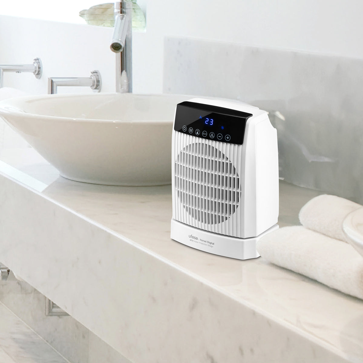 Termoventilatore digitale bianco per bagno su superficie in marmo. Lavabo e asciugamani dietro.