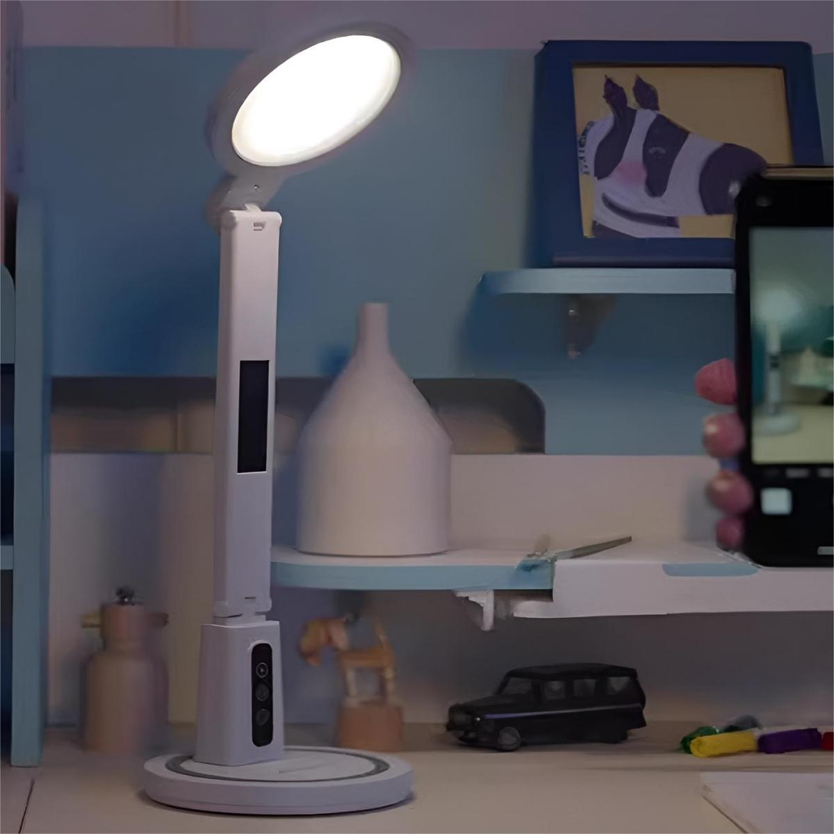 Eine Schreibtischlampe mit weißem Sockel und verstellbarem Kopf. Ein Telefon macht ein Foto der Lampe.