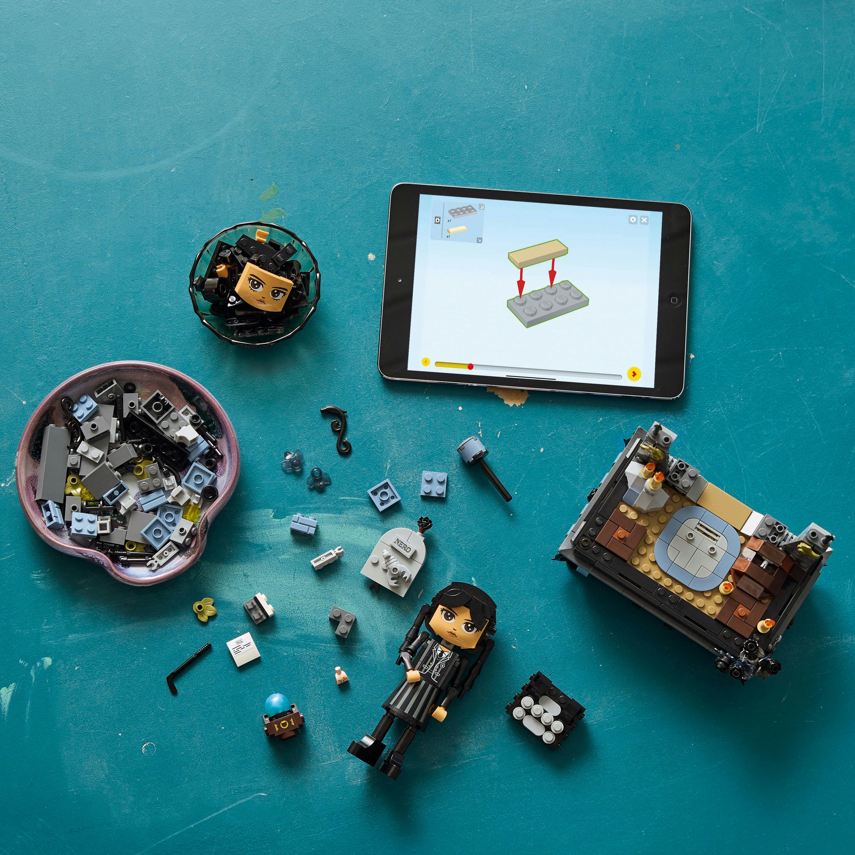 Elementy zestawu Lego w miskach, tablet pokazujący instrukcje i złożony zestaw Lego.