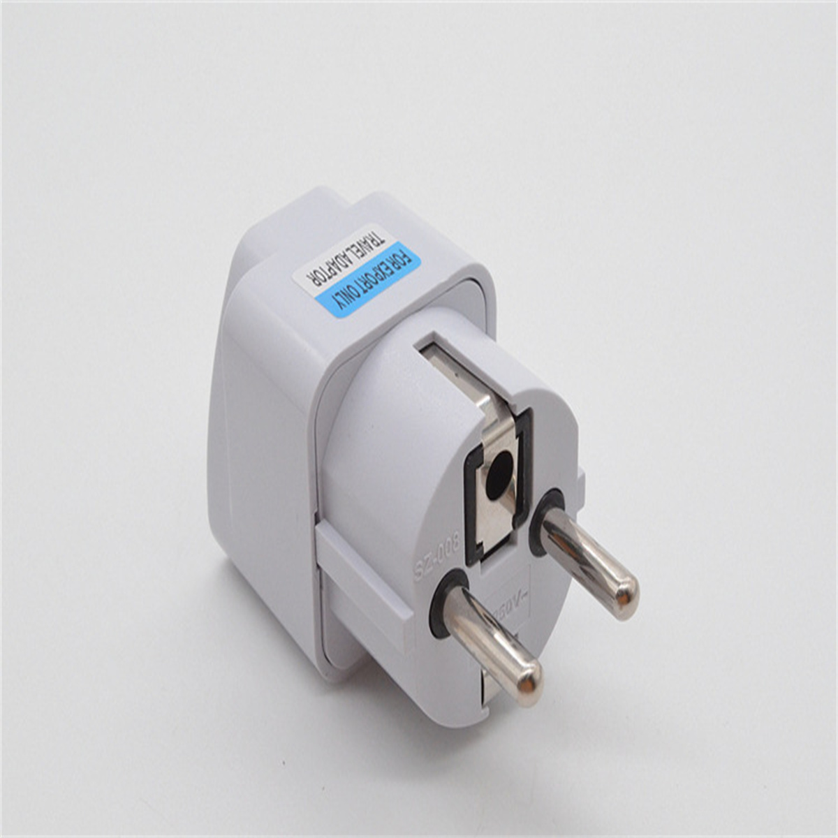 Ein weißer Reiseadapter mit zwei Stiften, gekennzeichnet für Export und Spannung.