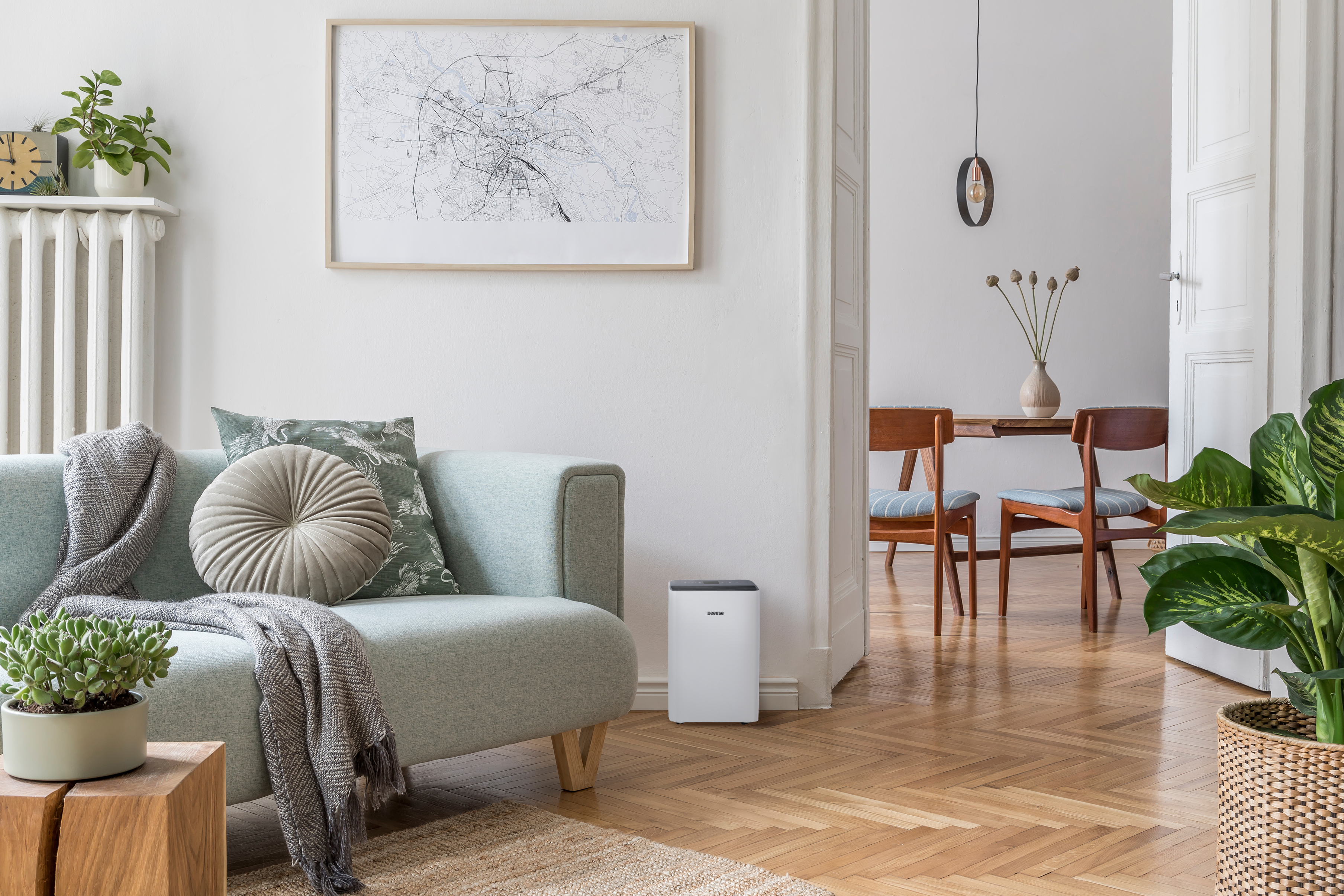 Ein Wohnzimmer mit Sofa, Pflanzen, einer Karte und Blick in einen Essbereich.